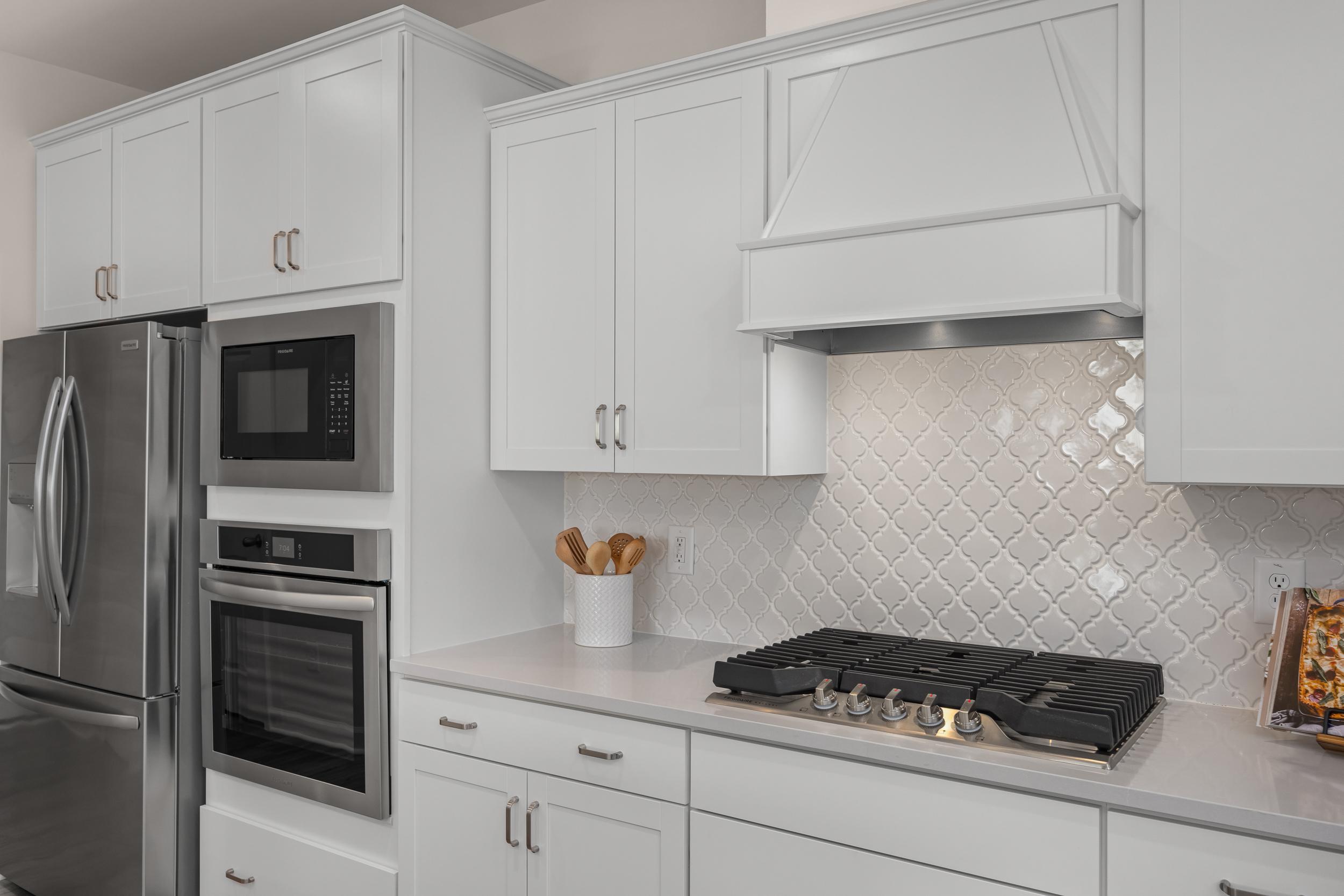 Spacious white kitchen in The Hickory II featuring shaker cabinets, stainless steel appliances, and subway tile backsplash