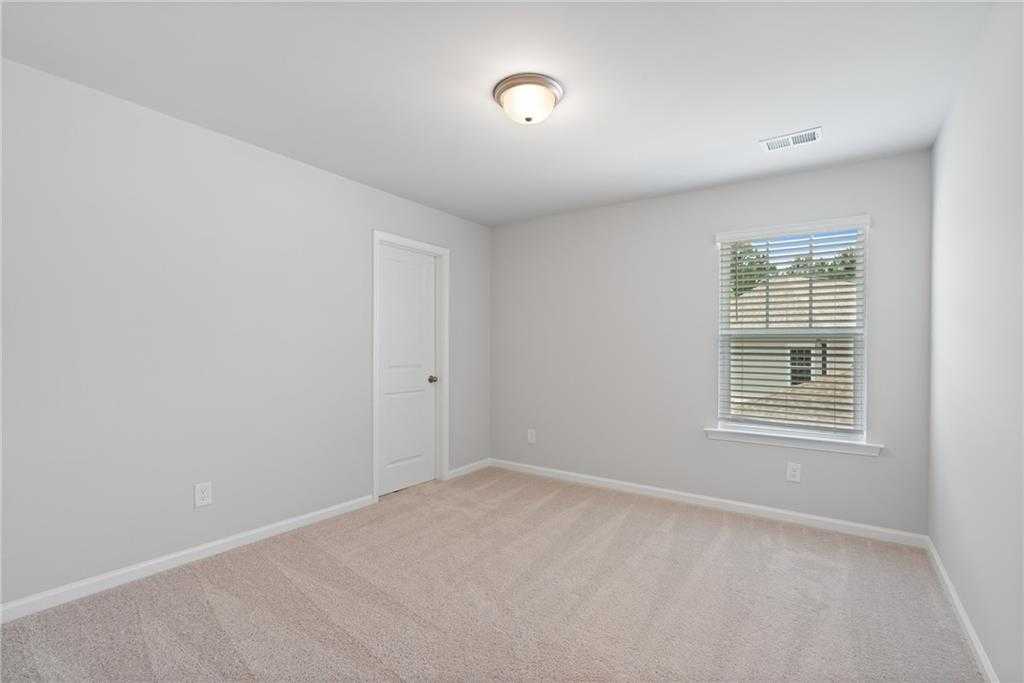 Bright secondary bedroom with light gray walls, beige carpet, and window blinds in Davidson Homes The Hickory B, Winder, GA