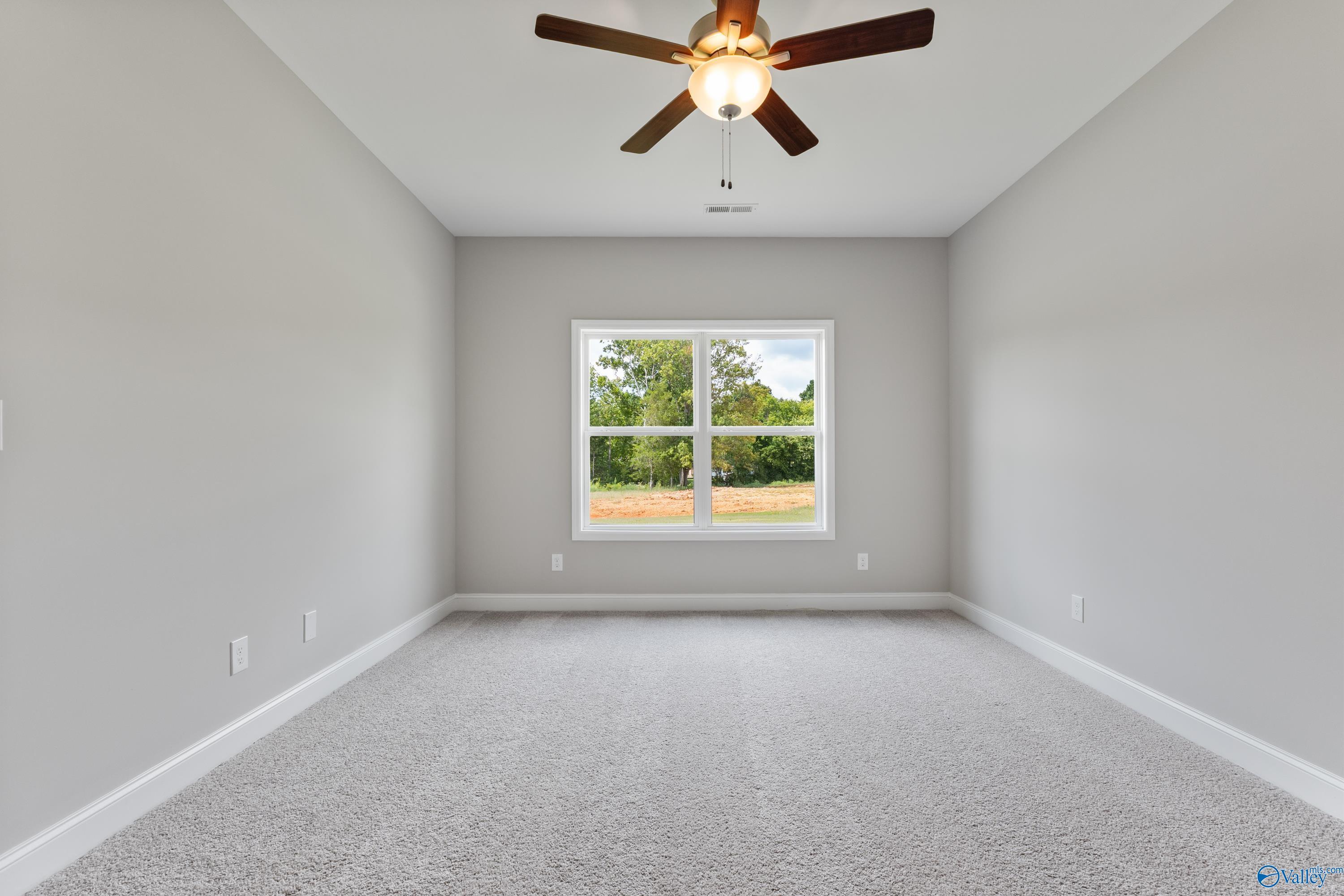 Bright secondary bedroom with ceiling fan, large window to green yard, gray walls and carpet in Davidson Homes The Franklin C, Huntsville, AL