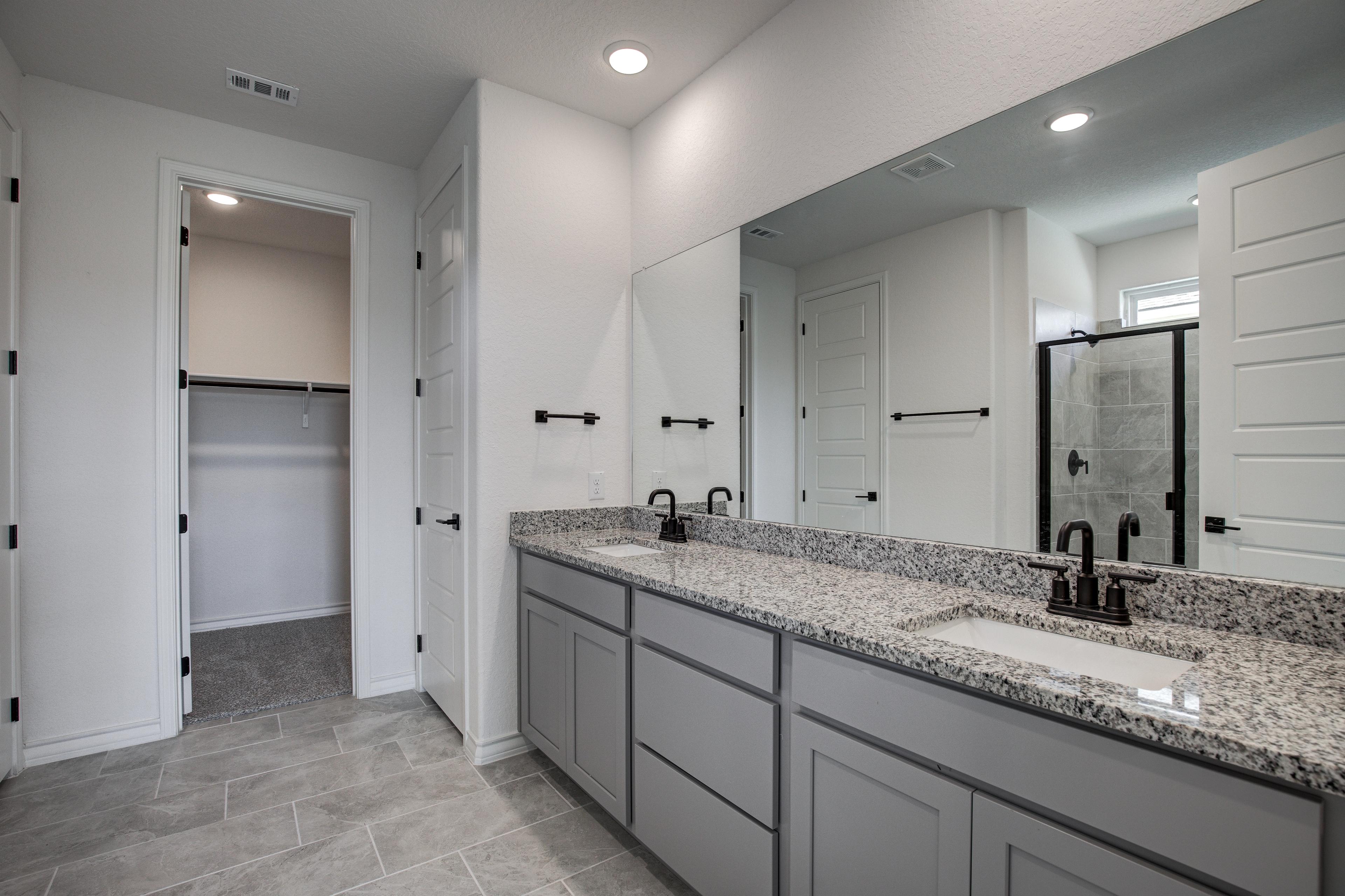 Luxurious master bathroom in The Lanier featuring double granite vanity, large mirror, and walk-in glass shower