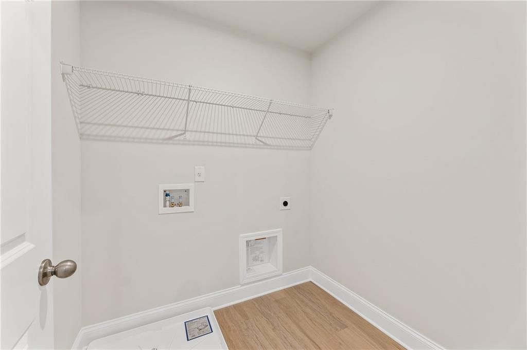 Laundry room with wire shelving, outlets, and hardwood floors in Davidson Homes The Willow B, Hoschton, Georgia
