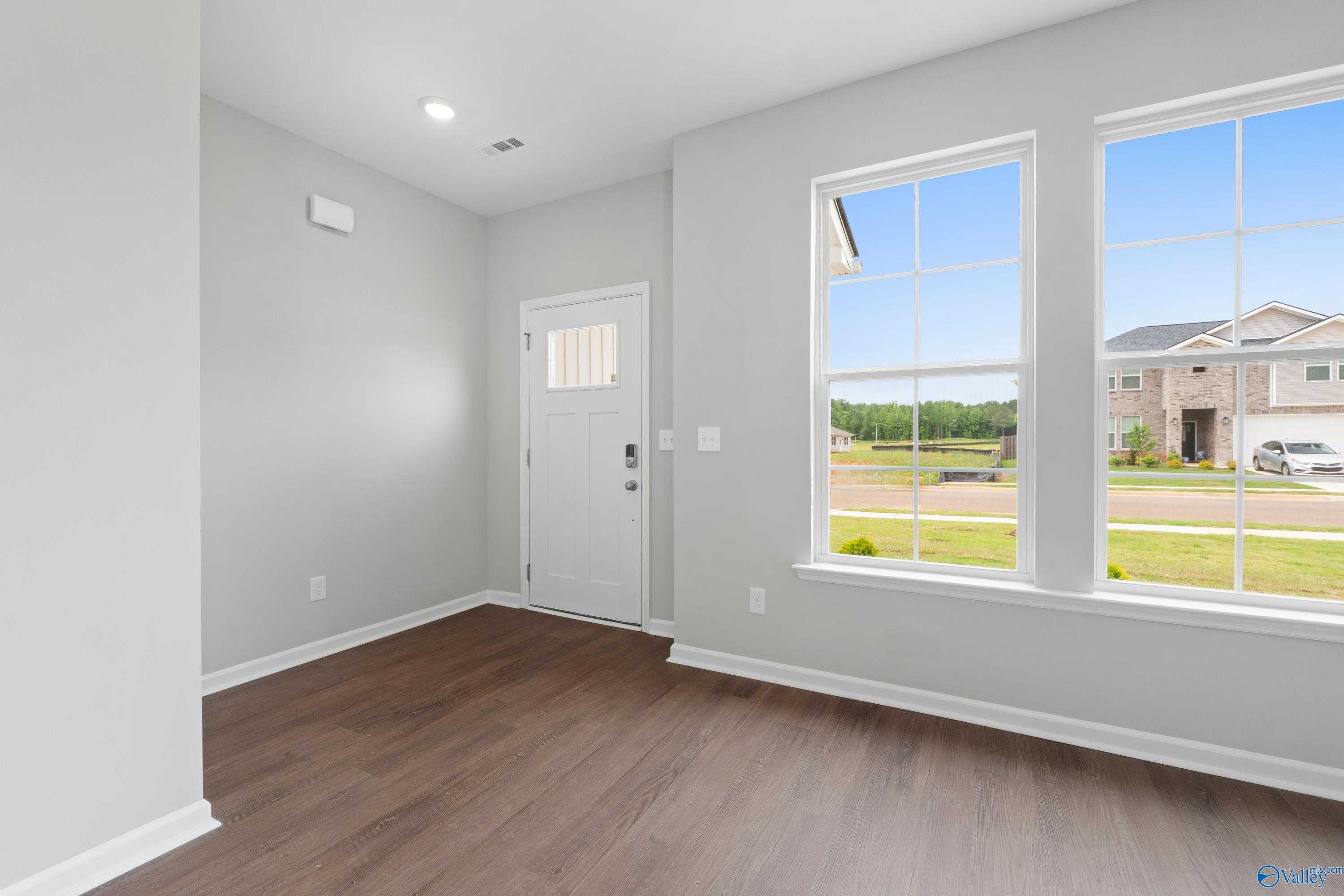 Bright entry foyer with hardwood floors, large windows, and green field view in Davidson Homes The Stella, Hazel Green, Alabama