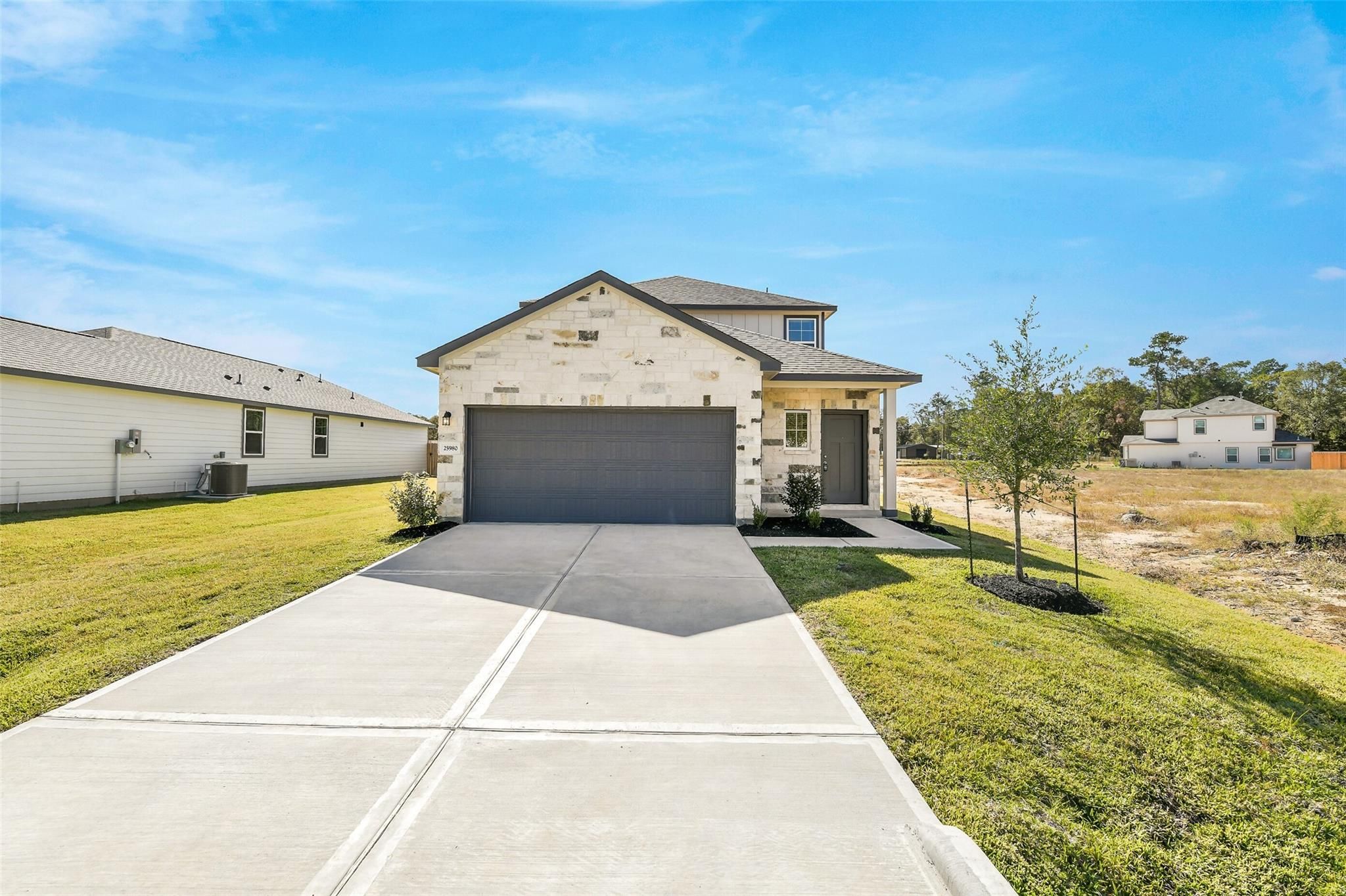 Two-story San Marcos E home by Davidson Homes in Liberty Estates, Cleveland, Texas, featuring stone facade, 2-car garage, and driveway