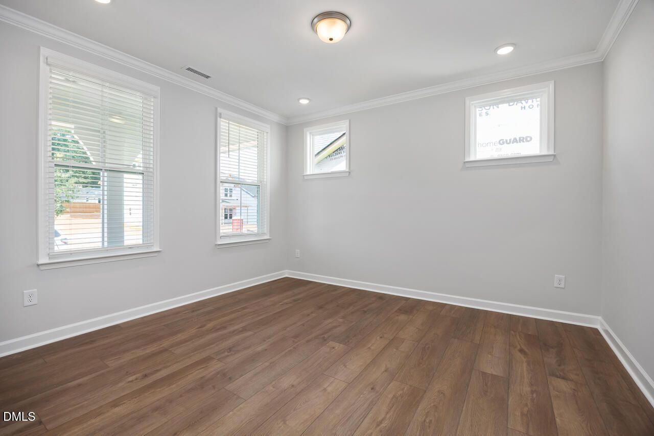 Bright bedroom with wood-style flooring in The Ashport L floor plan at Sage on North Main, Wake Forest, North Carolina.