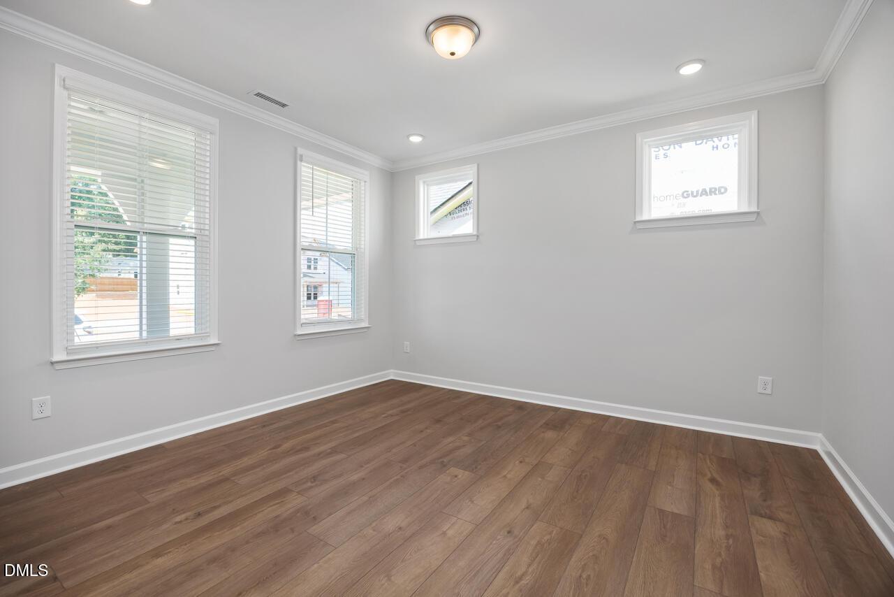 Bright bedroom with wood-style flooring in The Ashport L floor plan at Sage on North Main, Wake Forest, North Carolina.
