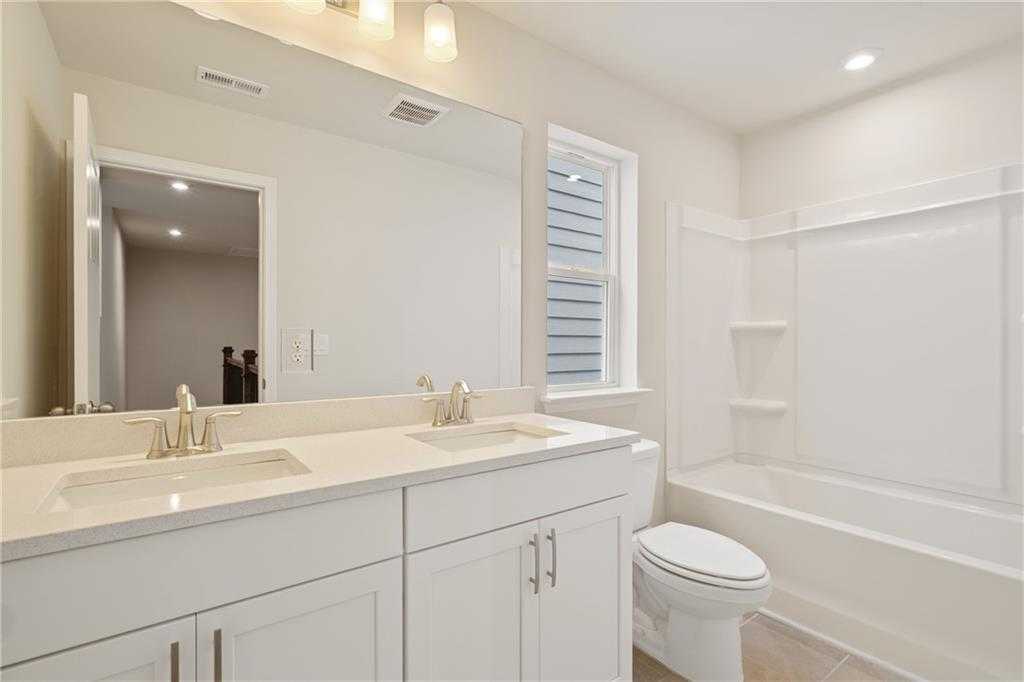 Bright bathroom with double vanity, white cabinets, tub-shower combo in Davidson Homes Cary B, Kennesaw, Georgia