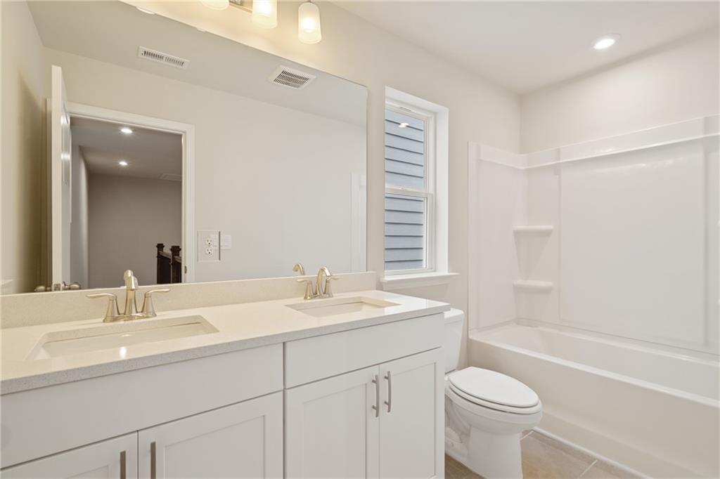 Bright bathroom with double vanity, white cabinets, tub-shower combo in Davidson Homes Cary B, Kennesaw, Georgia