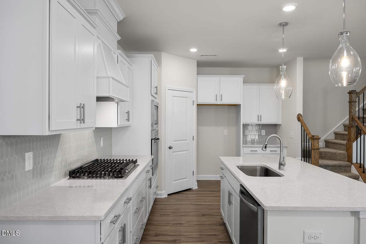 Modern white kitchen with quartz countertops, stainless steel appliances, gas range, and large island in Davidson Homes The Grace C, Lillington, NC