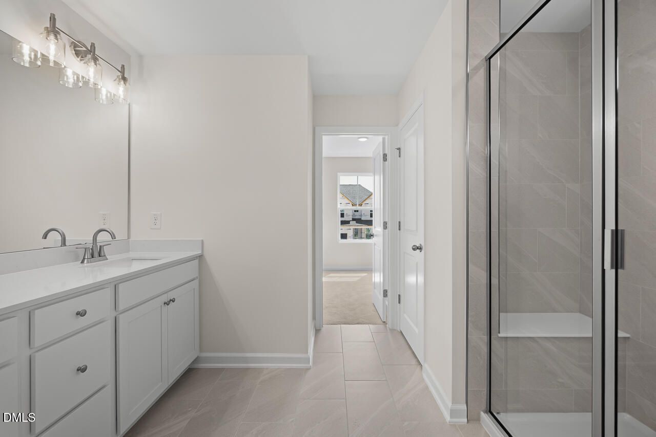 Modern bathroom with double vanity, glass tile shower, and white cabinetry in Davidson Homes Willow B plan, Zebulon NC