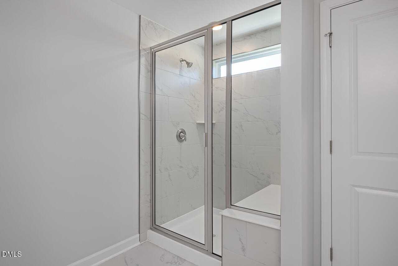 Frameless glass walk-in shower with white subway tiles and rainfall head in master bath of Davidson Homes The Graham, Fuquay-Varina, NC