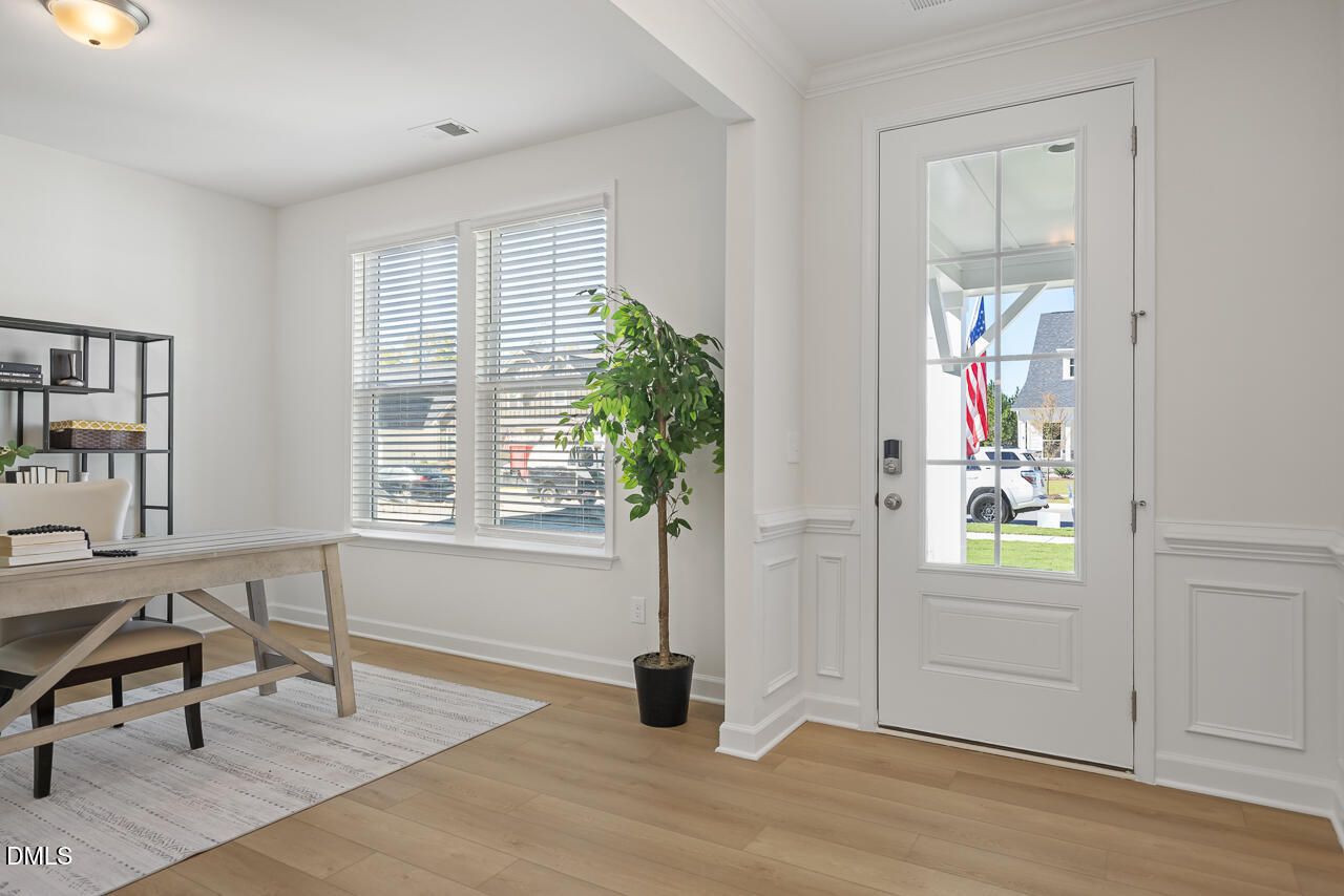 Bright foyer with glass-panel front door, wainscoting, and hardwood floors in Davidson Homes The Magnolia A, Wendell Ridge, NC