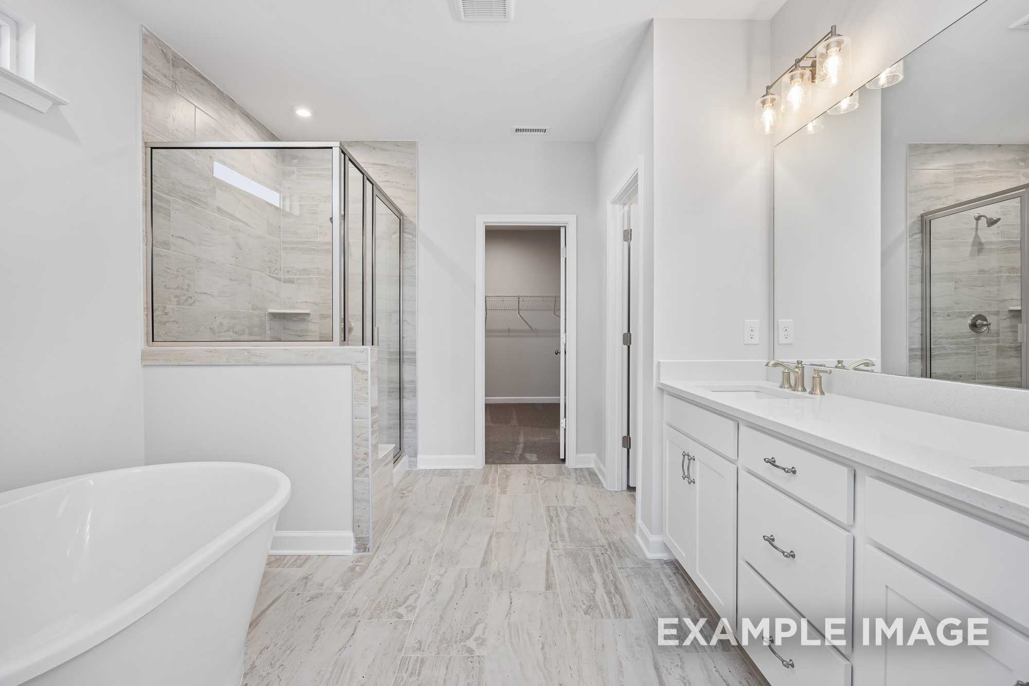 Spacious master bathroom in The Cypress D II with freestanding tub, glass shower enclosure, and white double vanity