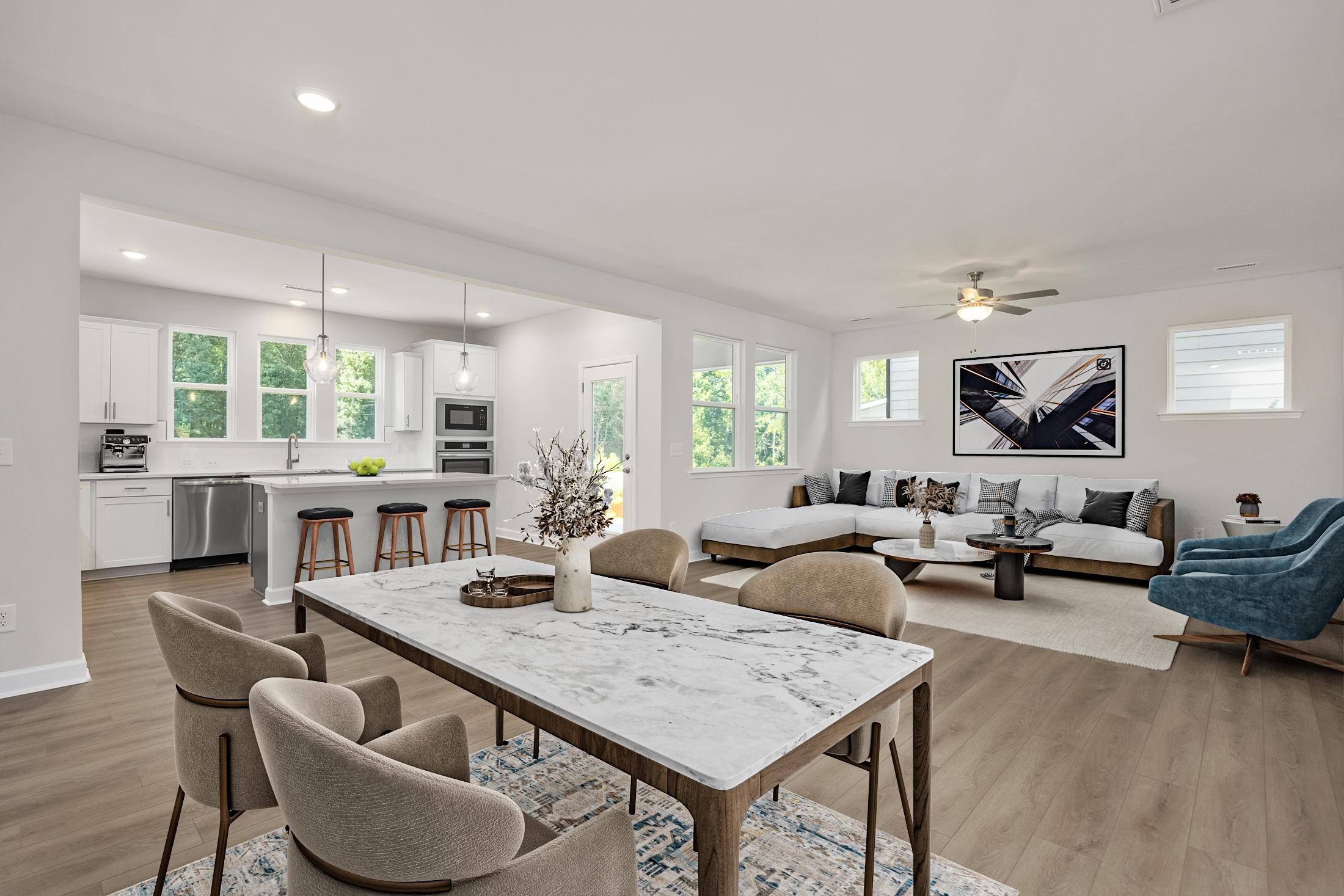 Open-concept kitchen dining living room in Ashland Apex NC by Davidson Homes featuring white cabinets marble island hardwood floors and neutral seating