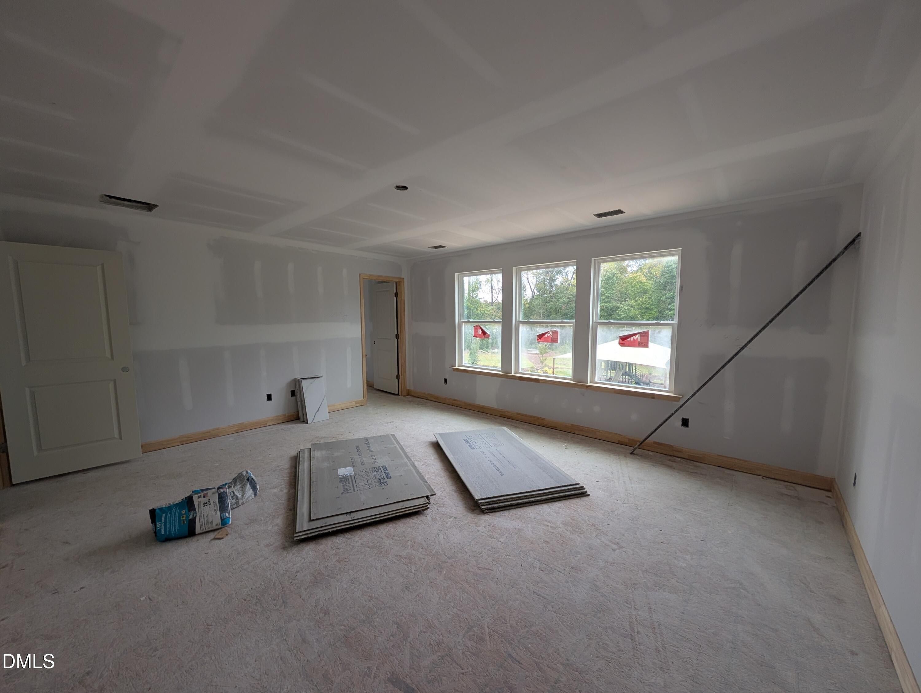 Unfinished bedroom under construction with three windows and tray ceiling in Davidson Homes The Beech plan, Wendell Ridge, NC