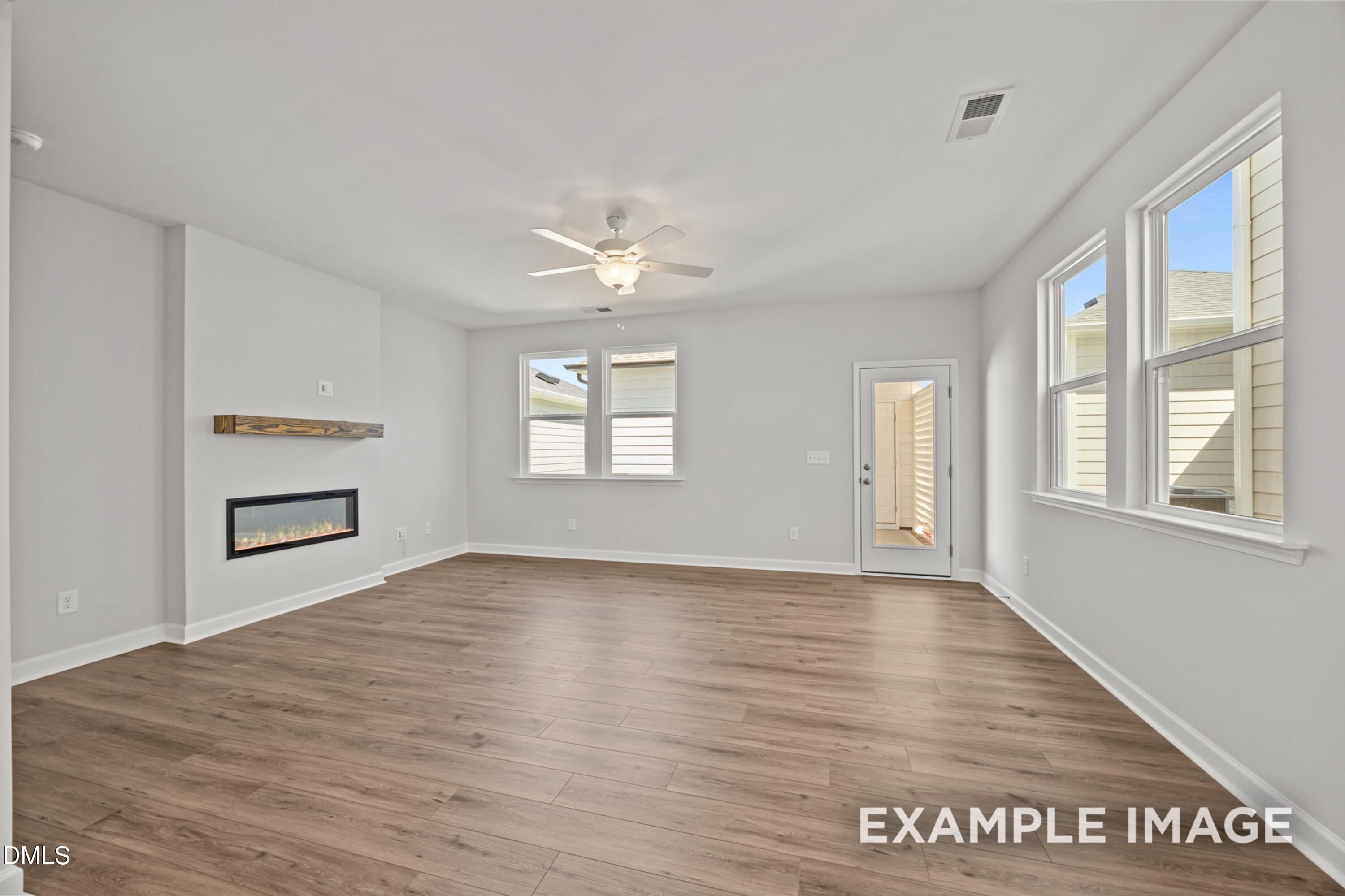 Bright living room with fireplace and wood-style flooring in The Alexander B floor plan at Forestville Yard, Knightdale.