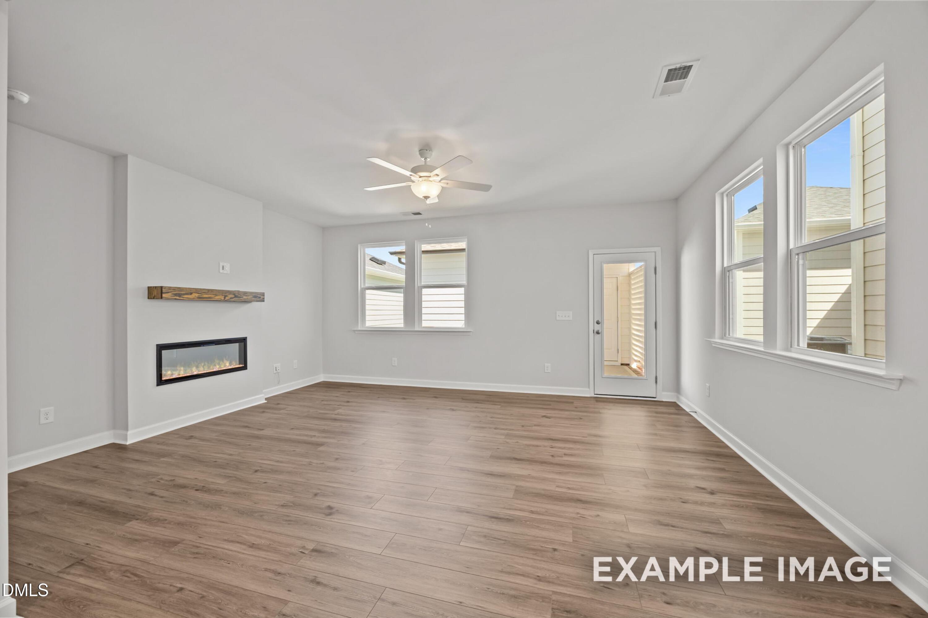 Bright living room with fireplace and wood-style flooring in The Alexander B floor plan at Forestville Yard, Knightdale.