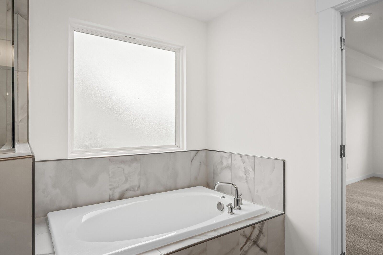 Modern soaking tub with marble tile surround in The Henry C floor plan bathroom at Benders Cove, Mt. Juliet, Tennessee.