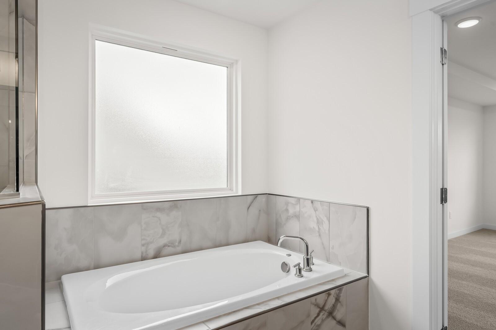 Modern soaking tub with marble tile surround in The Henry C floor plan bathroom at Benders Cove, Mt. Juliet, Tennessee.