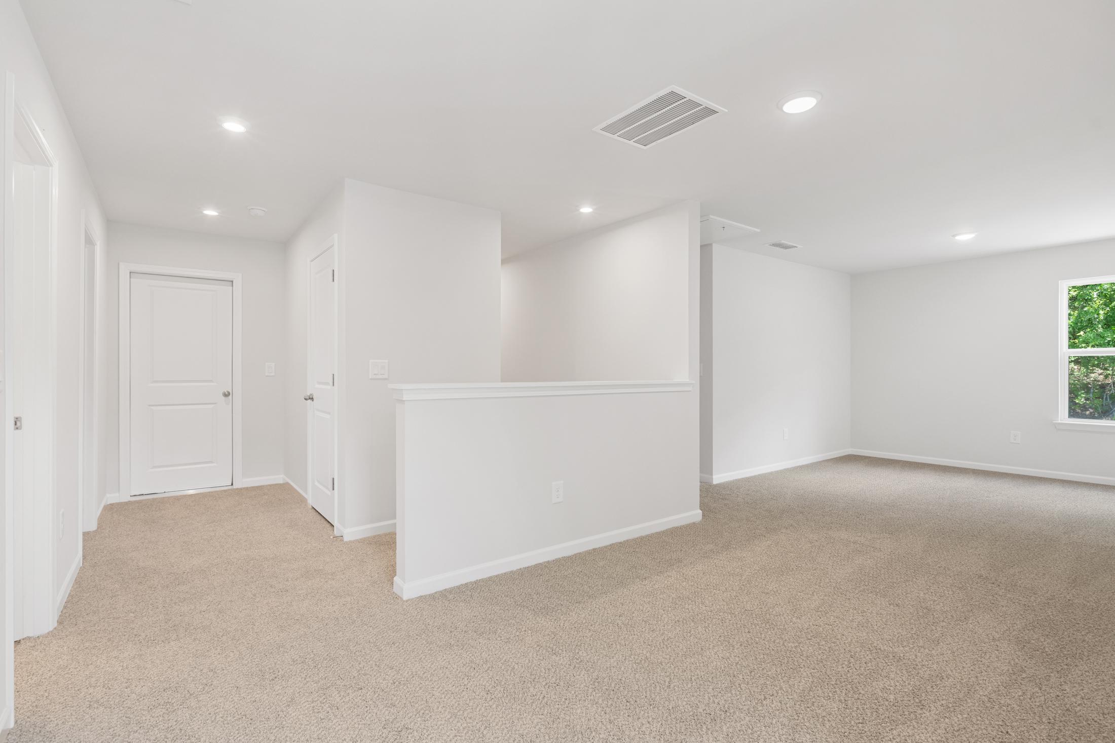 Spacious upstairs hallway at Mountainbrook in Cartersville GA with white walls, beige carpet, and open railing