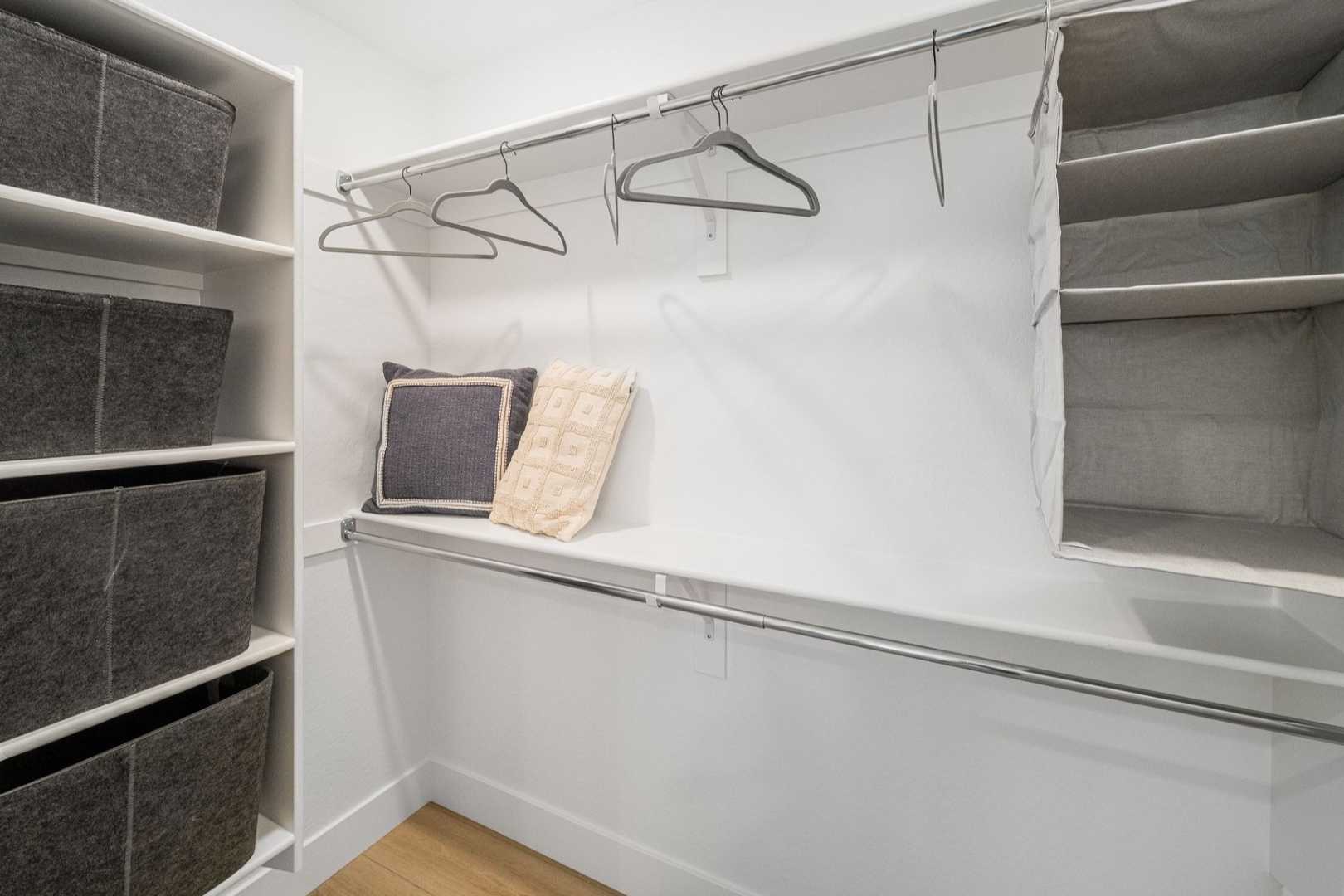 Spacious master walk-in closet in The Wilmington with white walls, gray fabric bins, hanging rods, shelves, and hardwood floors