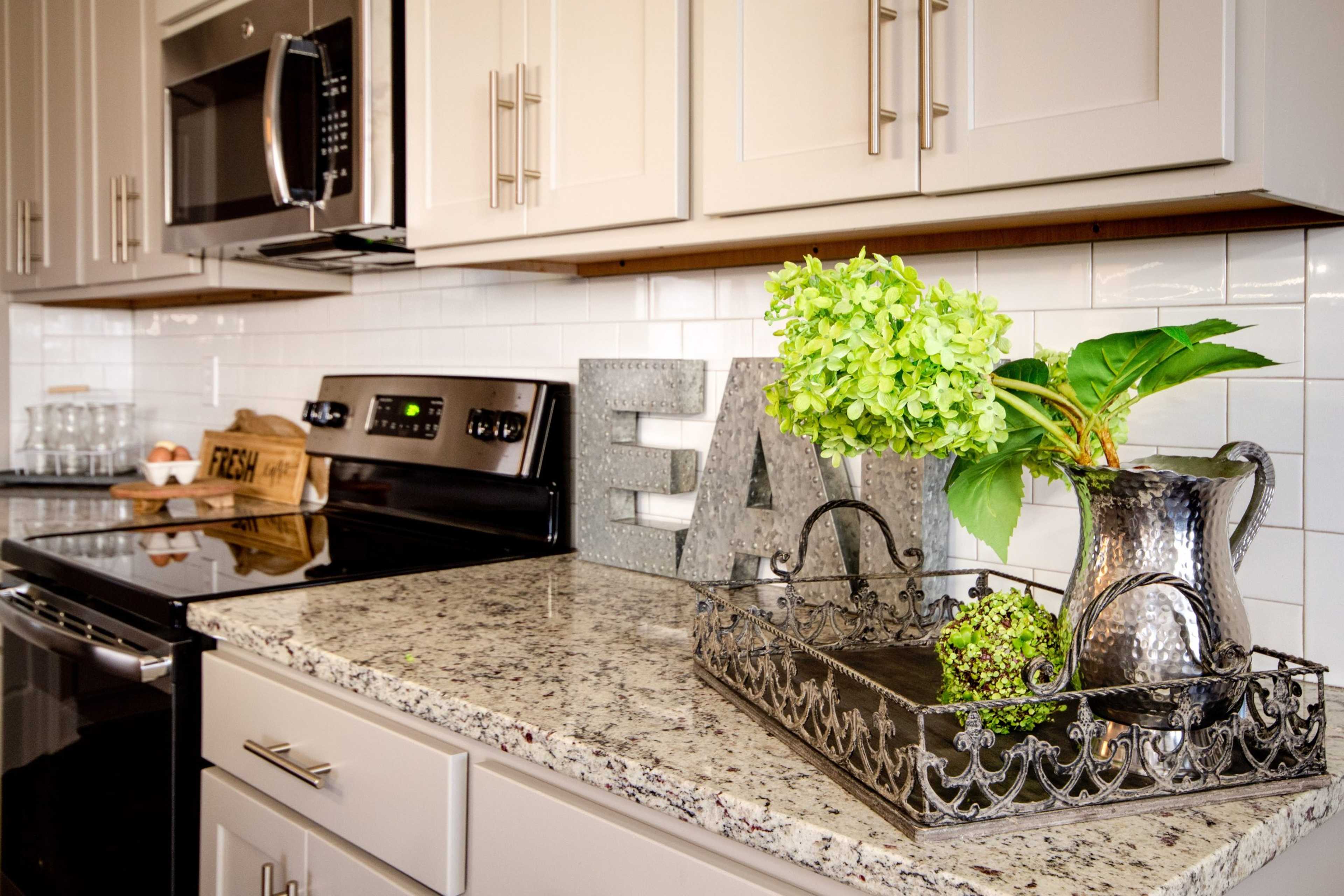 Spacious kitchen at Bakers Farm in Priceville Alabama featuring white shaker cabinets granite countertops stainless steel appliances and floral decor