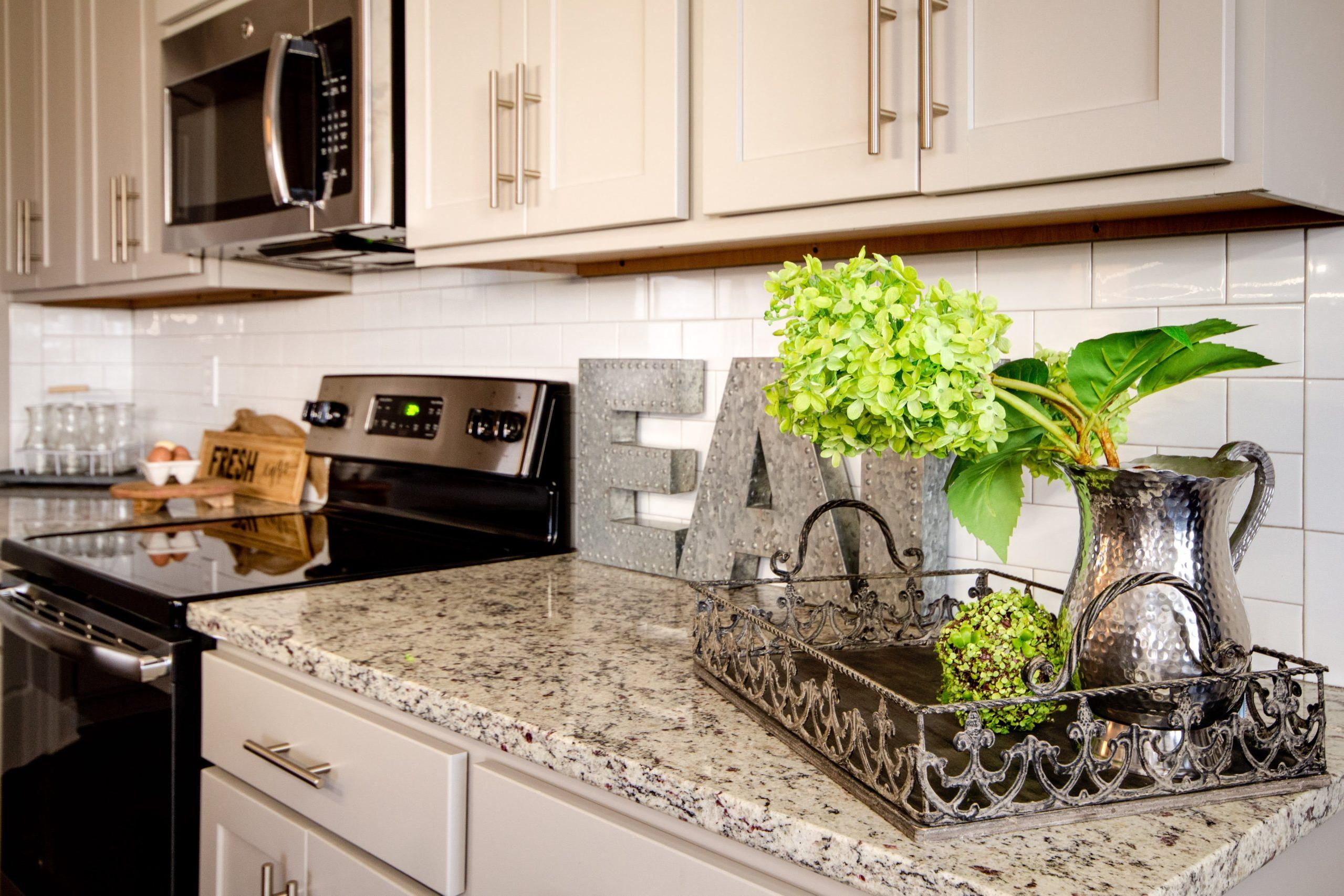 Spacious kitchen at Bakers Farm in Priceville Alabama featuring white shaker cabinets granite countertops stainless steel appliances and floral decor