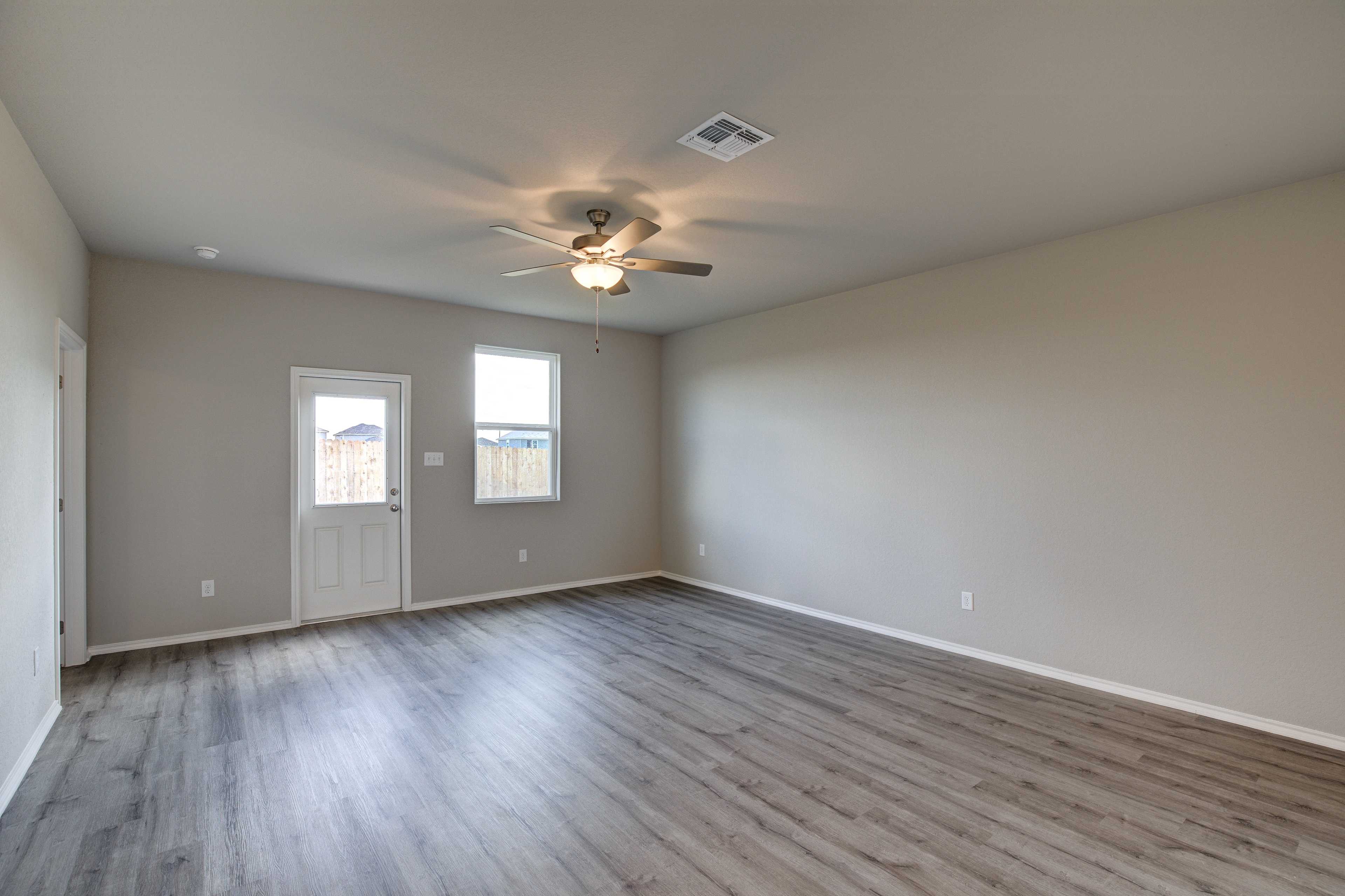 Spacious living room in The Blanco B featuring ceiling fan, large windows, beige walls, and luxury vinyl plank flooring