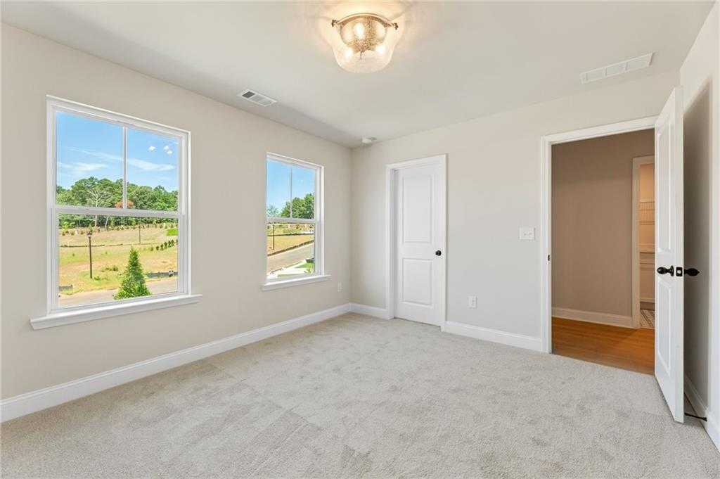 Bright bedroom with large windows overlooking green fields and trees in The Hickory E, Davidson Homes, Buford, GA