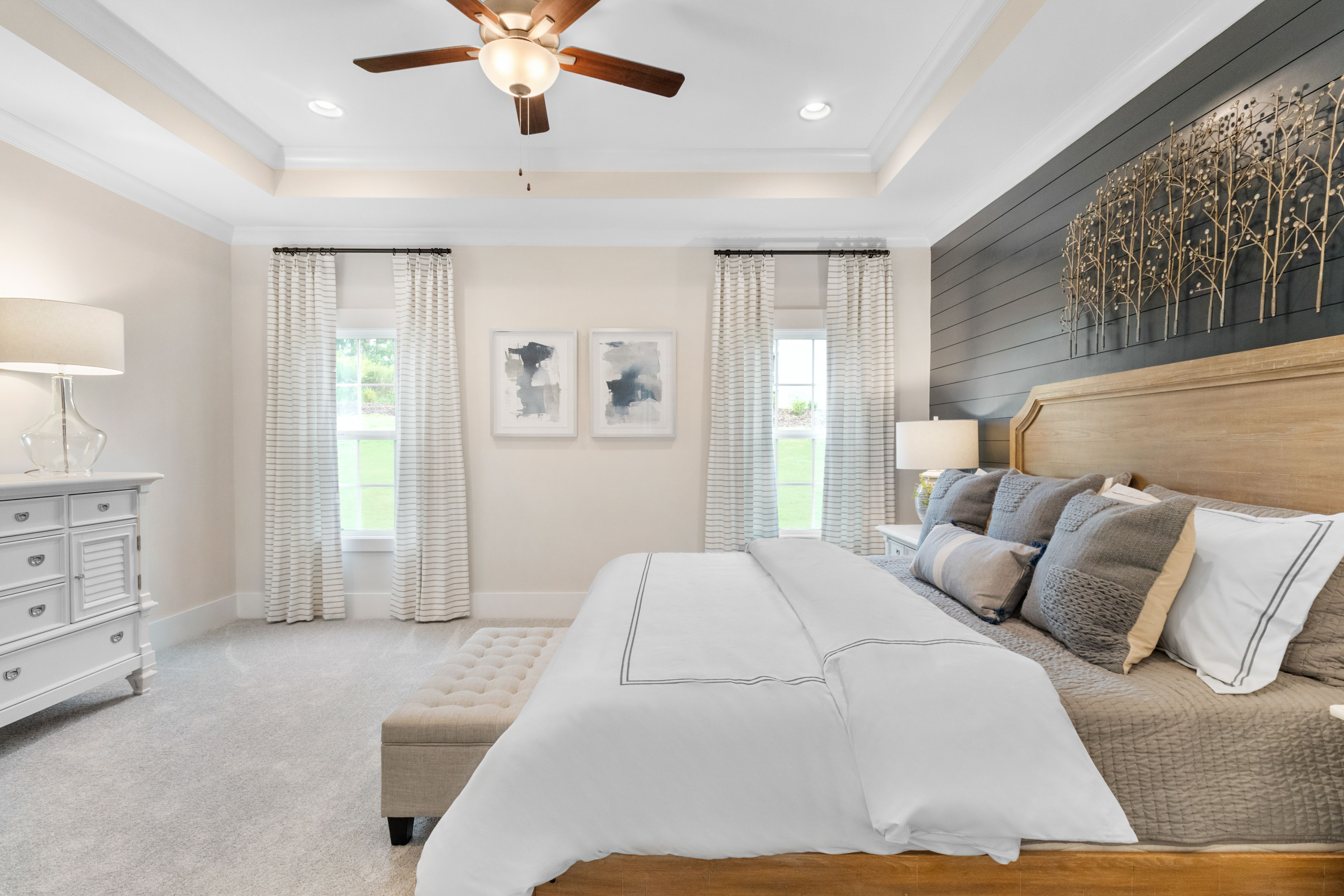 Spacious master bedroom in Noble Ridge, Cullman Alabama with king bed, wooden accent wall, and sheer-curtained windows
