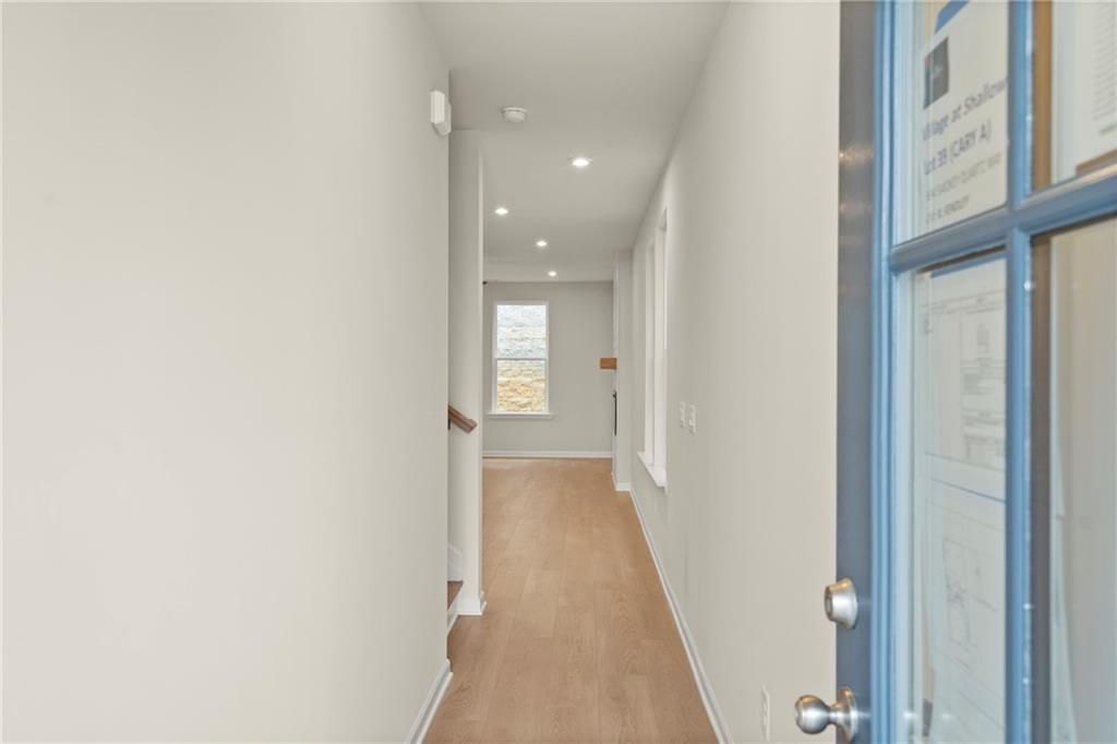 Bright hallway with hardwood floors, staircase, and glass door in The Cary A 3-bedroom home, Kennesaw, Georgia