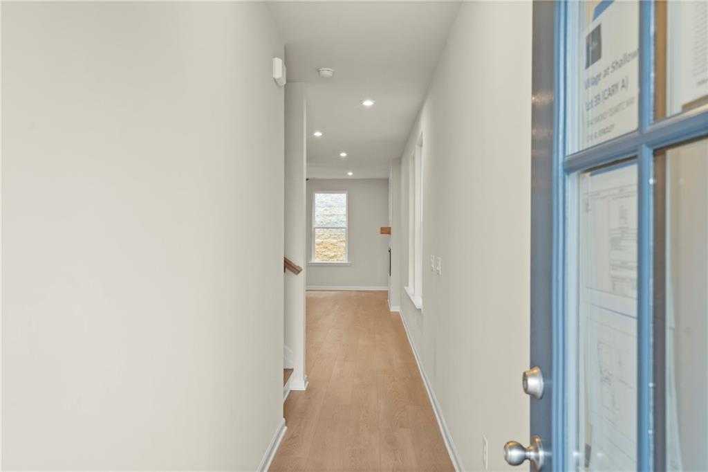 Bright hallway with hardwood floors, staircase, and front door in Davidson Homes Cary A, Winder, Georgia