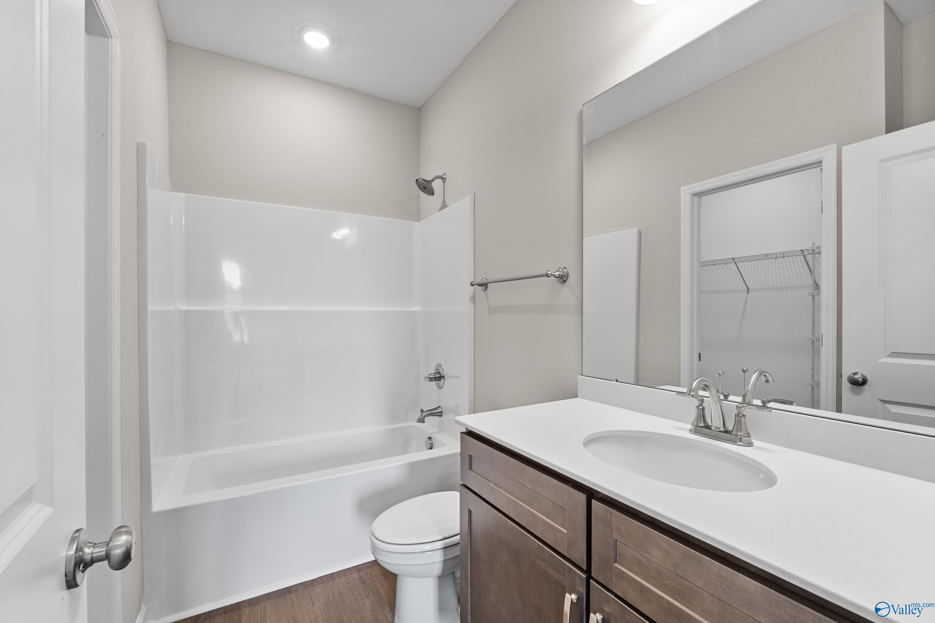 Modern bathroom with white tub-shower combo, vanity sink, large mirror in The Sanctuary 4-bedroom home, Riverton Preserve, Huntsville, AL