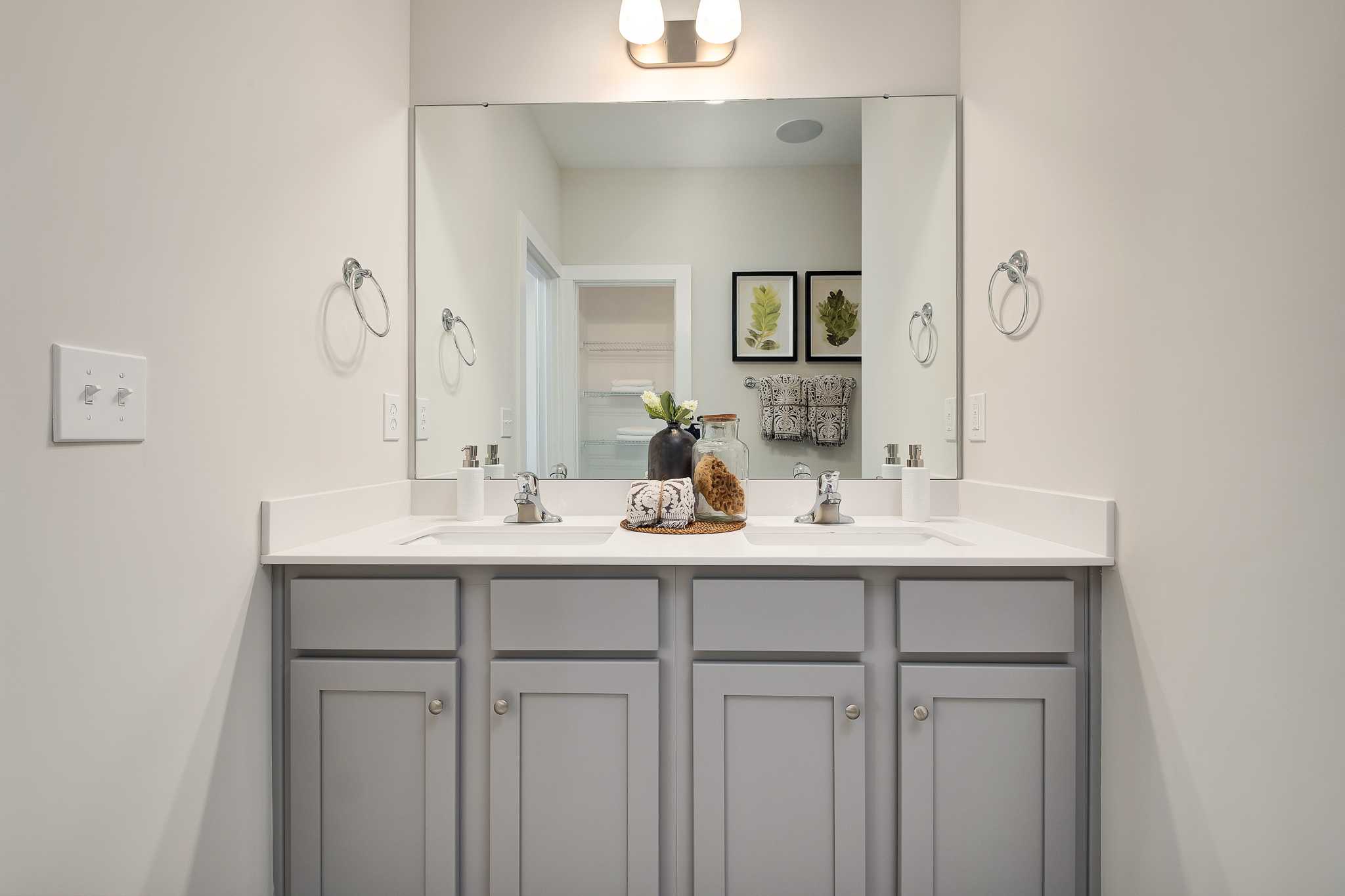 Spacious double vanity bathroom at Magnolia Preserve in Hartselle, Alabama with gray shaker cabinets, modern mirror and lighting