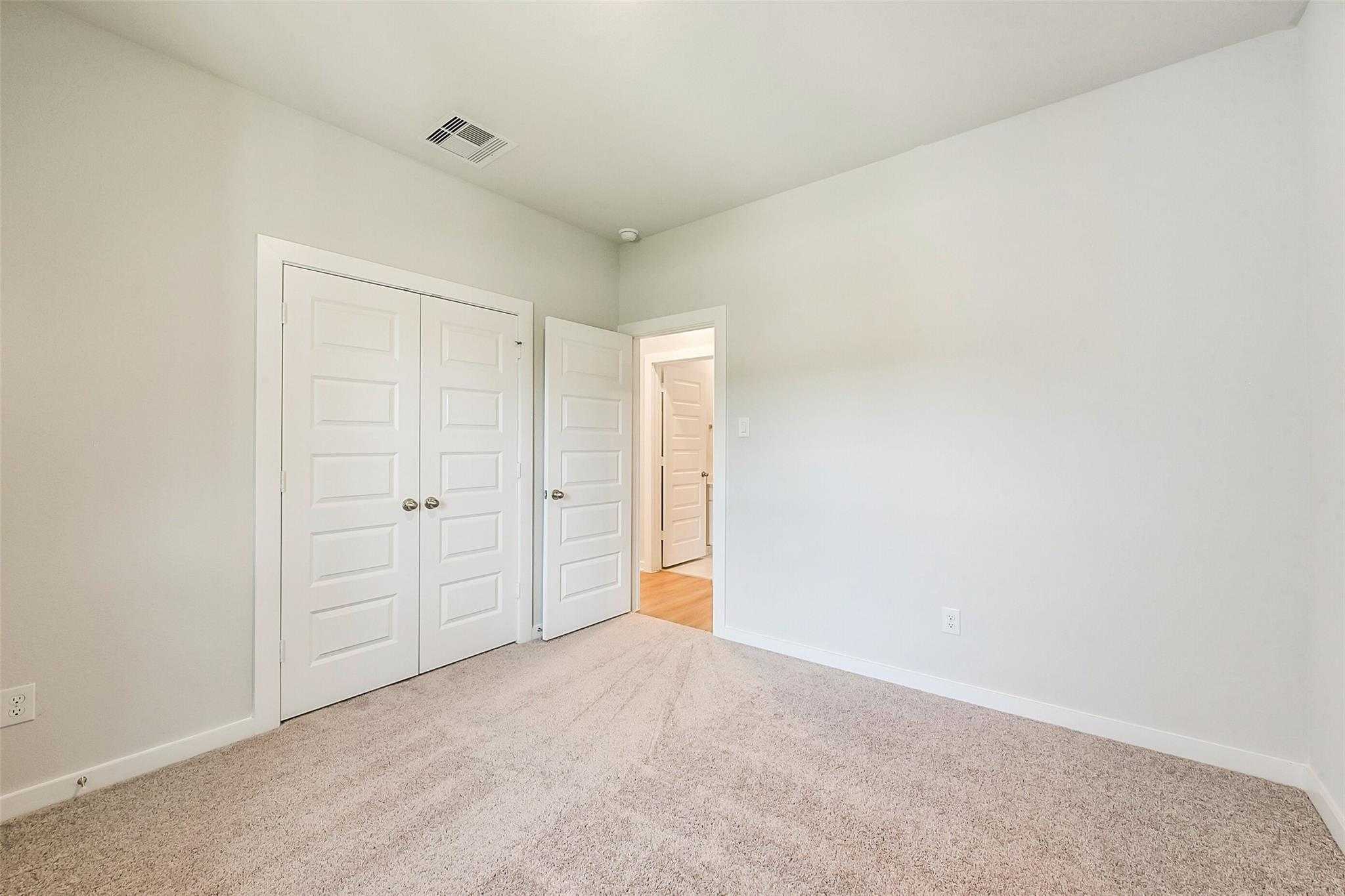 Spacious secondary bedroom featuring double closet doors and en-suite bath access in Davidson Homes Comal G, Dayton Texas