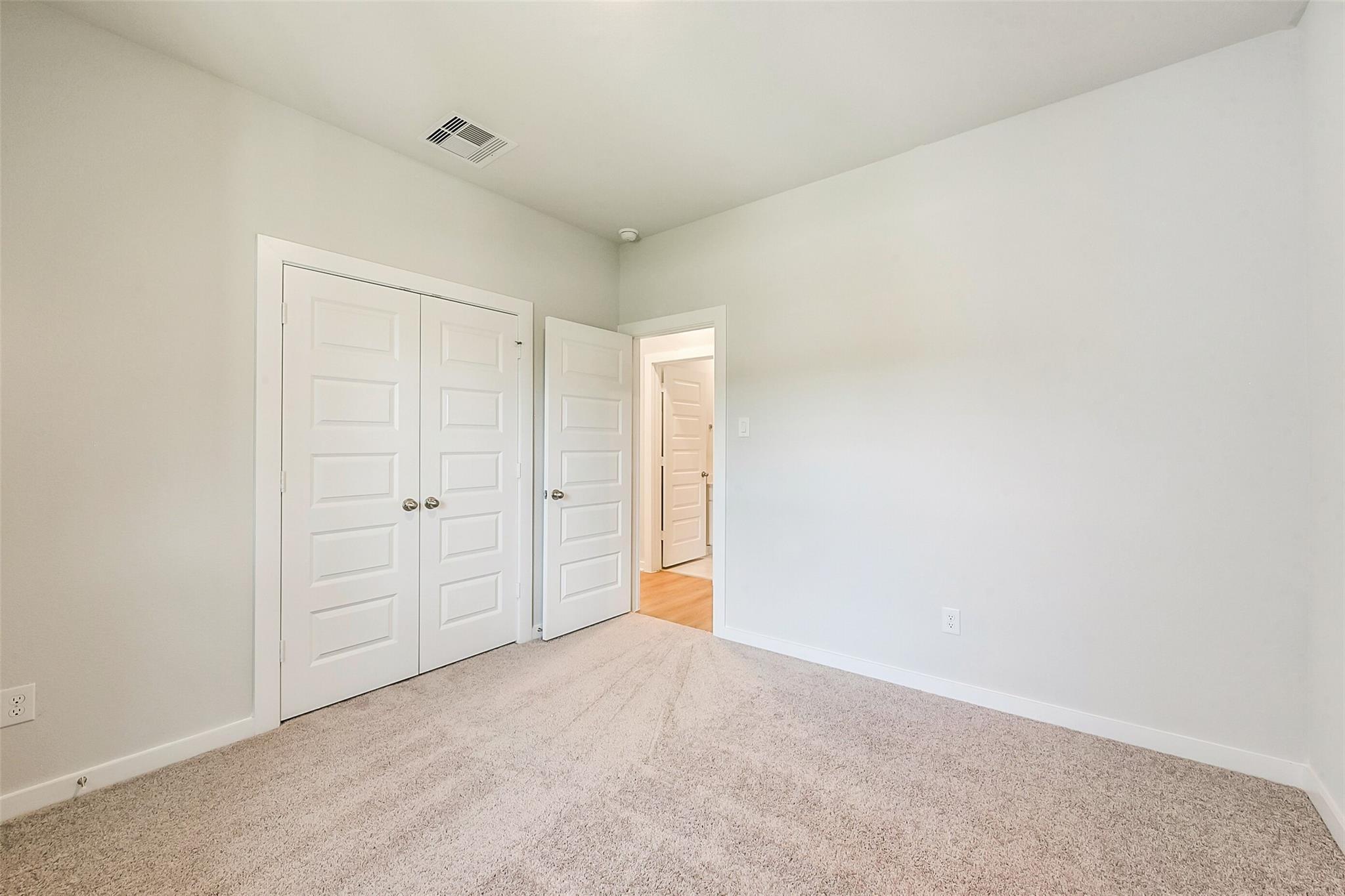 Spacious secondary bedroom featuring double closet doors and adjacent bath in Davidson Homes The Comal G, Dayton Texas