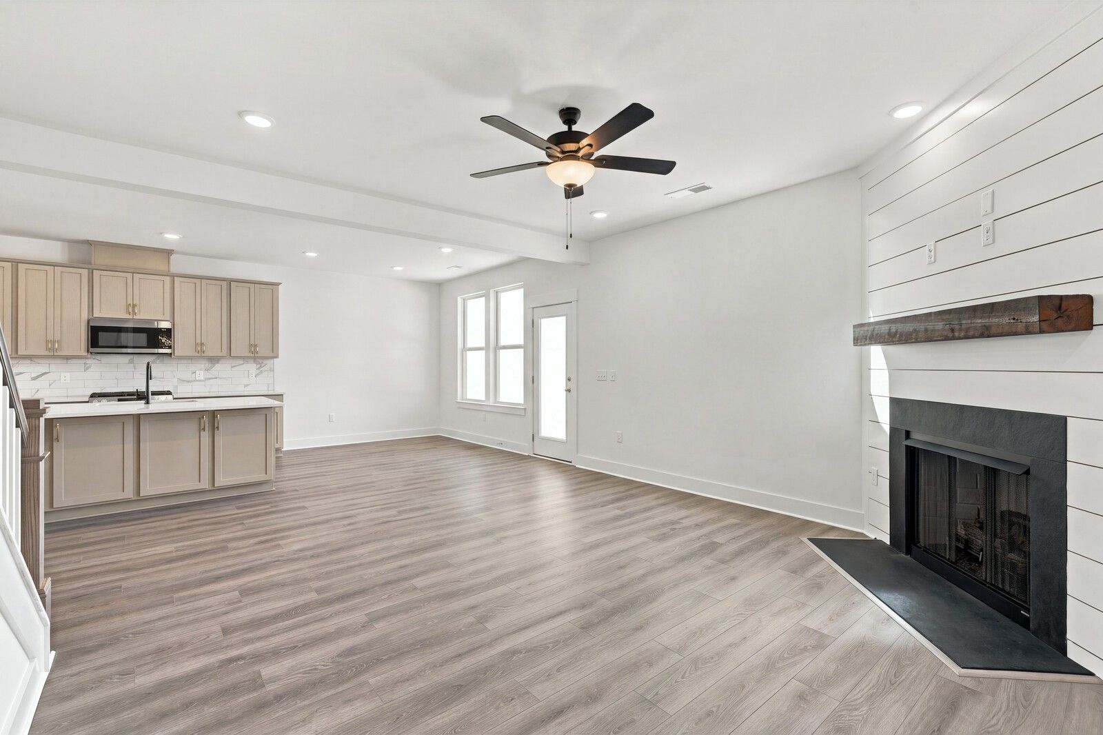 Open-concept living room with shiplap fireplace and kitchen in Davidson Homes The Willow B, Woods Crossing, Gallatin, TN