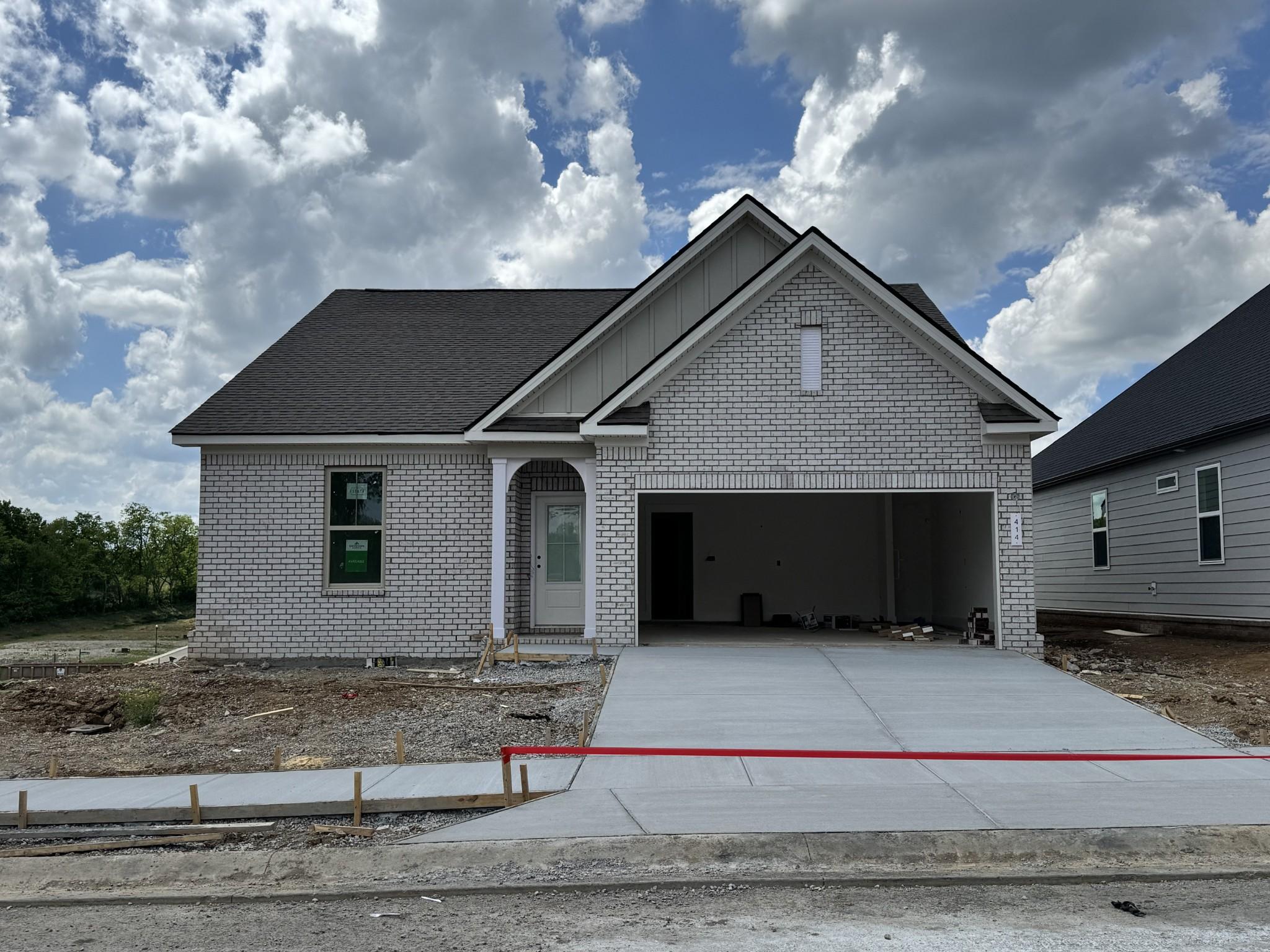 Modern gray brick 1-story home with open 2-car garage, gabled roof in Woods Crossing, Gallatin, Tennessee by Davidson Homes Prairie C