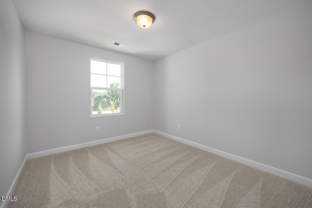 Bright, carpeted bedroom with neutral walls in The Graham floor plan at Springvale, Fuquay-Varina, North Carolina.