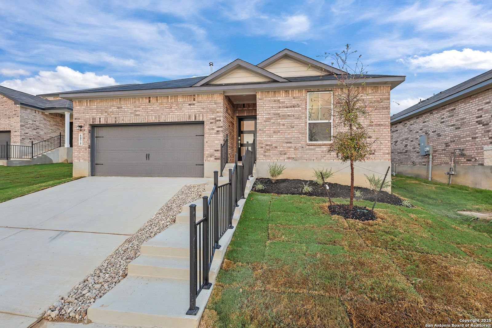 Modern brick single-story home with 2-car garage, front entrance, and landscaped yard in Comanche Ridge, San Antonio, Texas - Davidson Homes Asheville J