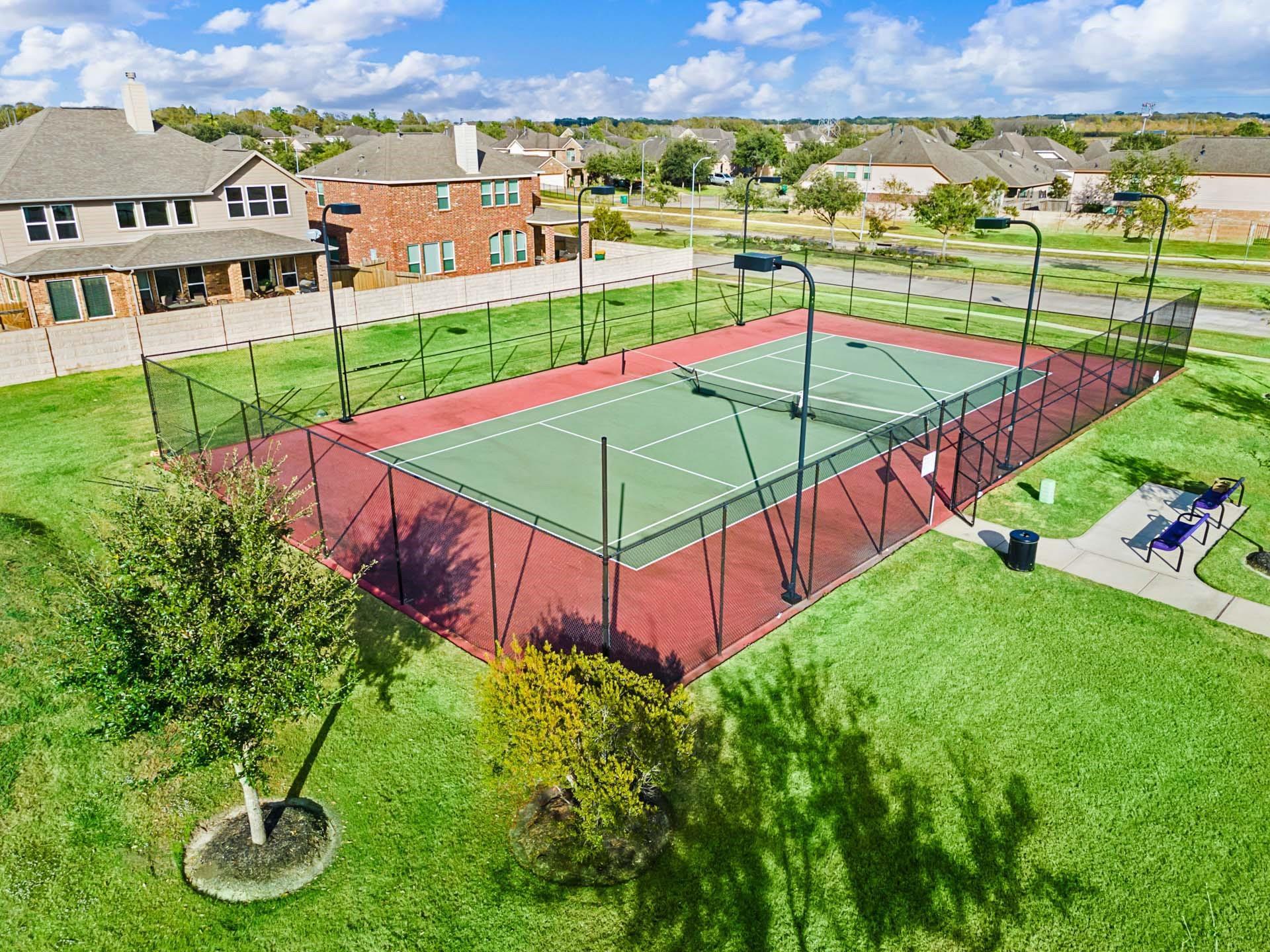 Tennis court with green surface and red perimeter in Sierra Vista community, Rosharon, Texas near Davidson Homes properties.