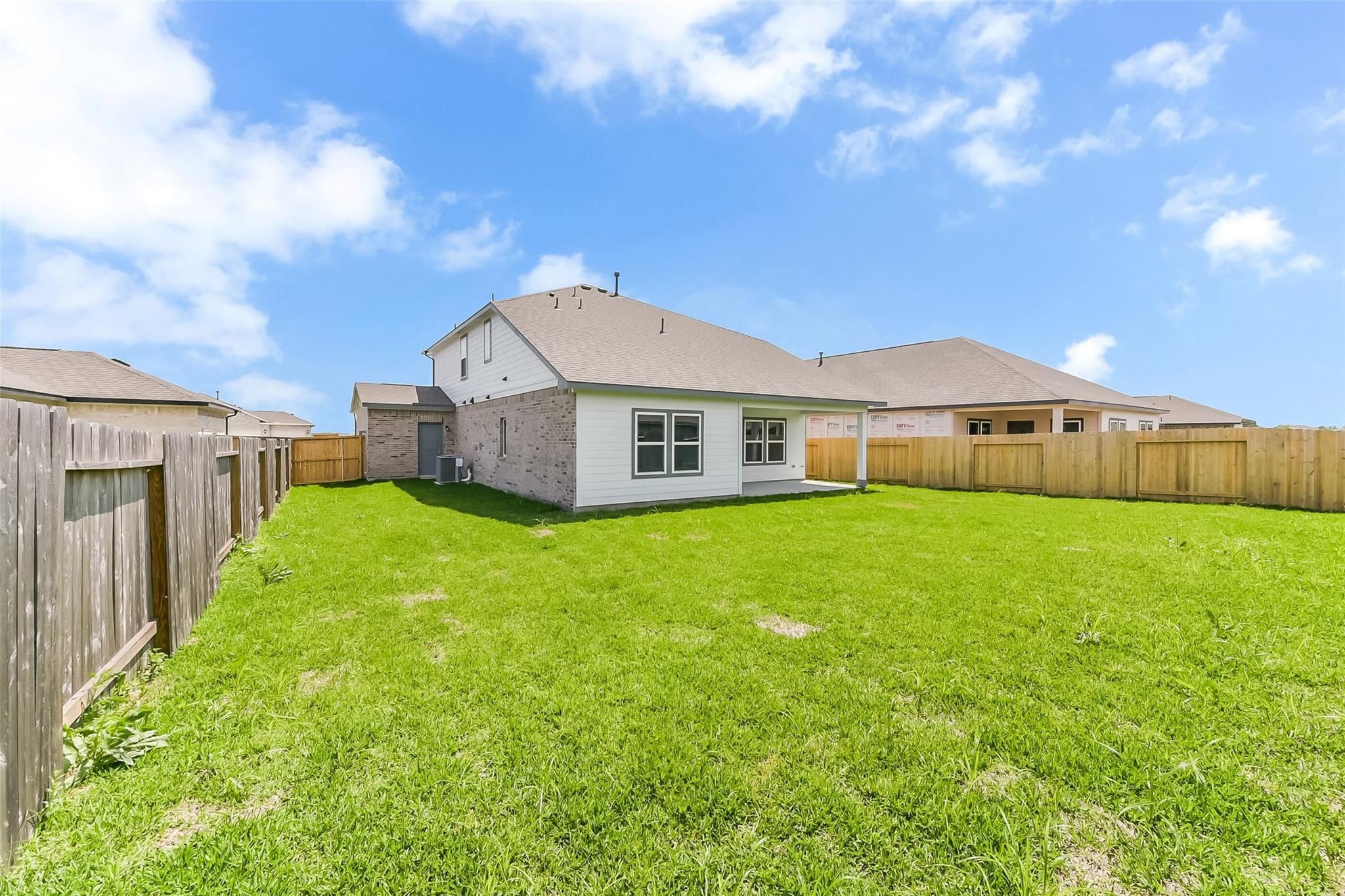 Spacious green backyard with wooden privacy fence behind 2-story 4-bedroom home in River Ranch Meadows, Dayton, Texas