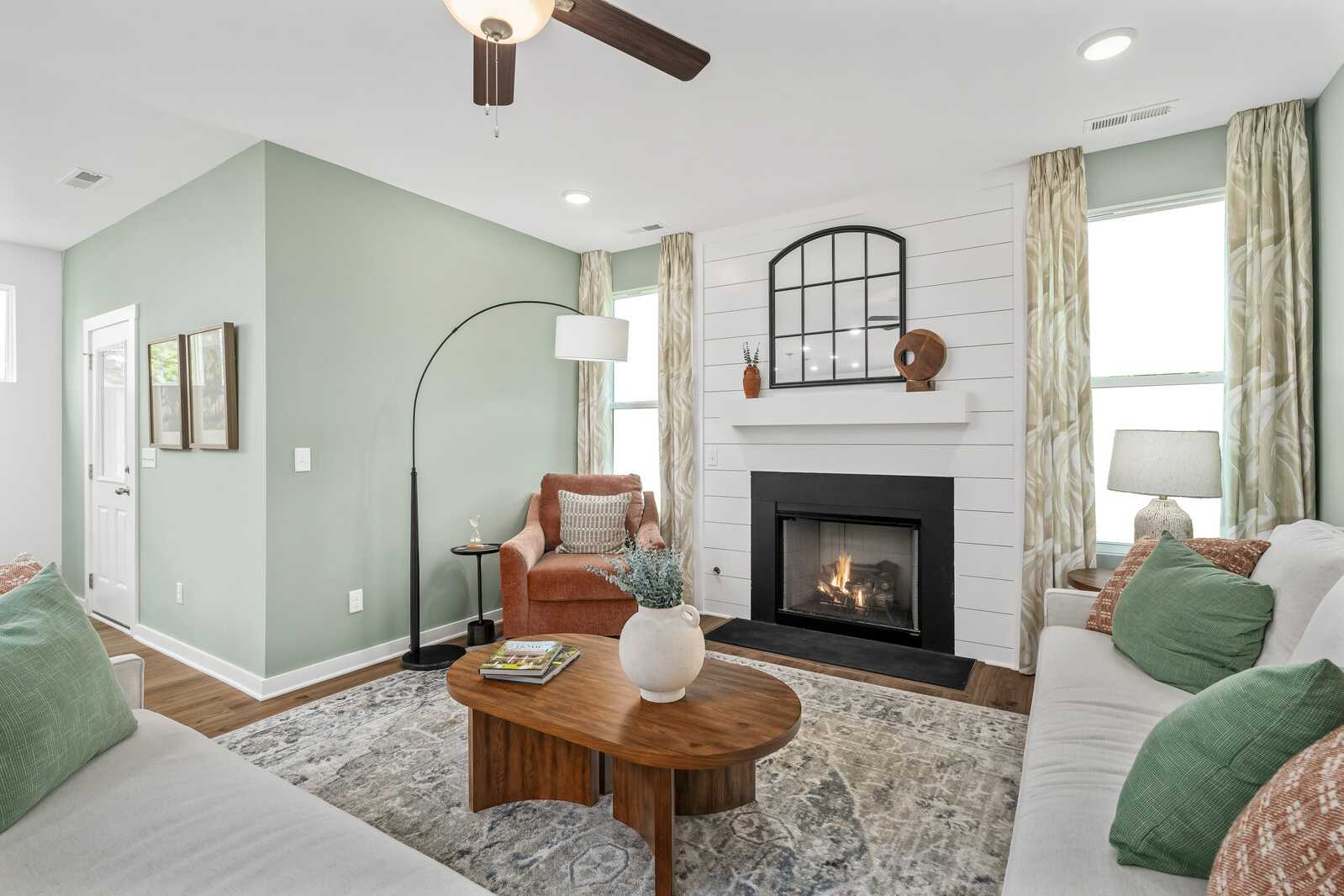 Cozy living room in Calista Farms White House TN with gas fireplace, shiplap accents, green walls, and plush sofa