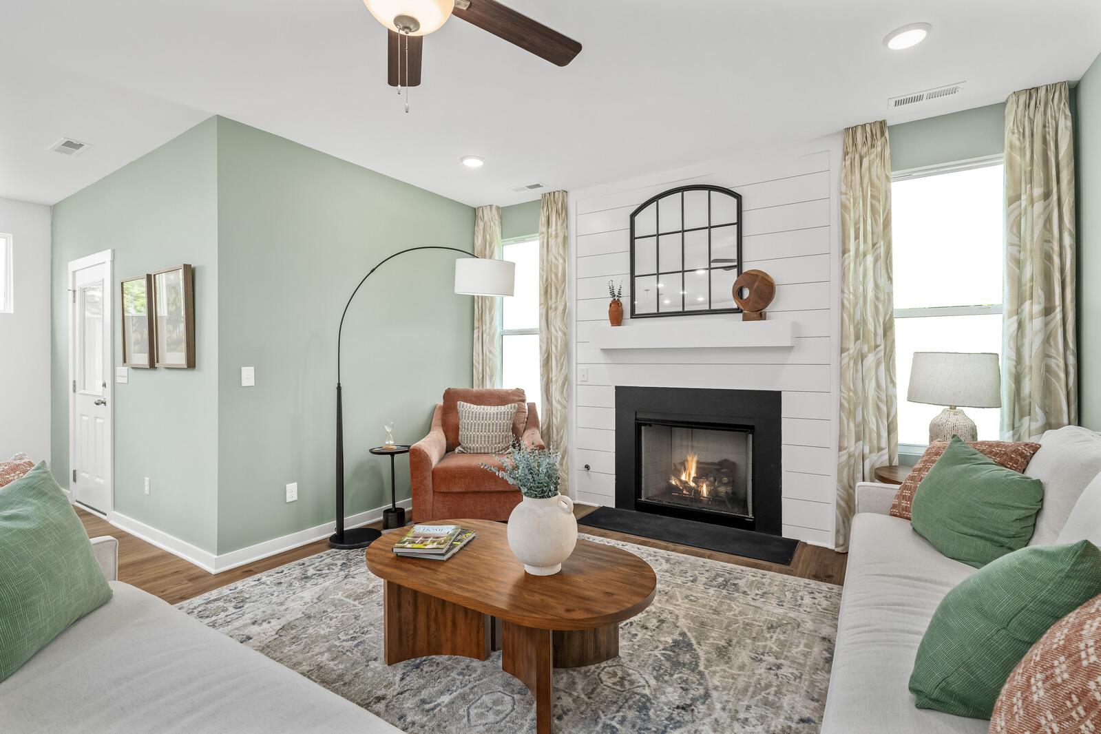 Cozy living room in Calista Farms White House TN with gas fireplace, shiplap accents, green walls, and plush sofa