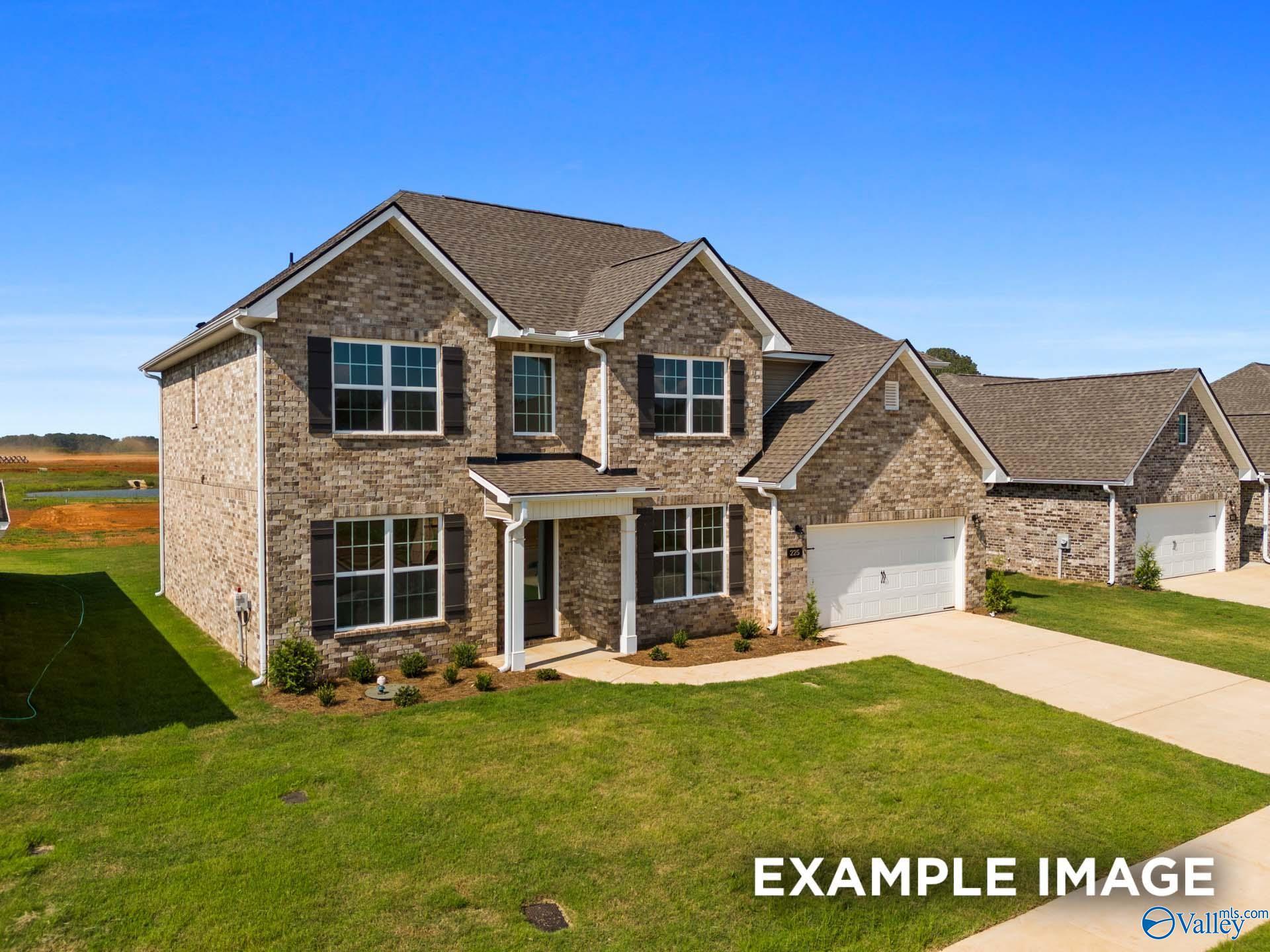 Brick 1.5-story home with shingle roof, 2-car garage, front porch, and landscaped lawn in Kendall Downs, Toney, Alabama