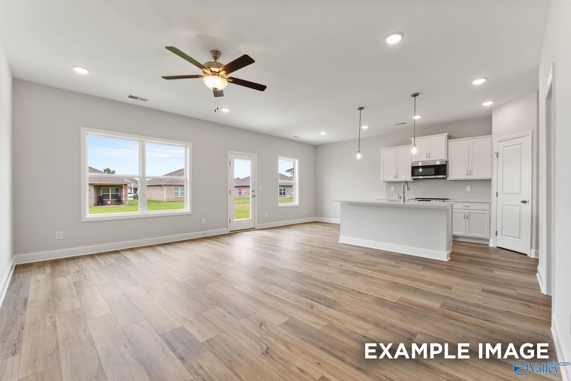 Open-concept living room and kitchen with white cabinets in The Butler floor plan at Heritage Lakes, New Market, Alabama.