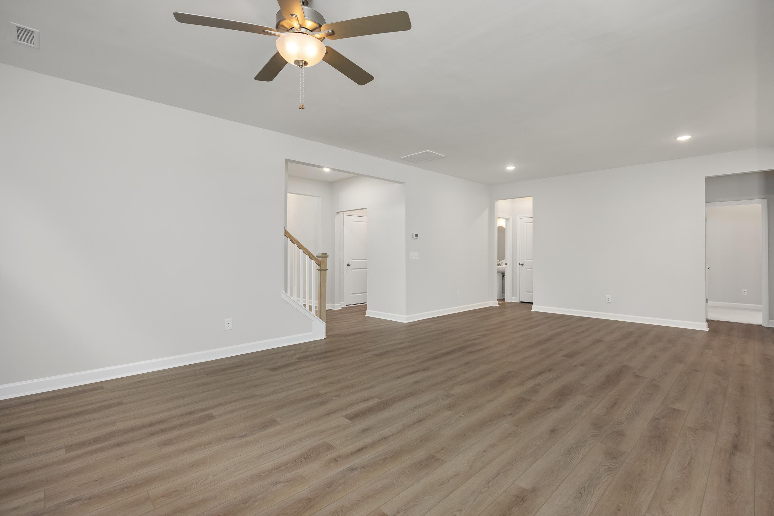 Spacious upper floor hallway in The Aspen C home with light wood floors, white walls, arched doorways, and ceiling fan