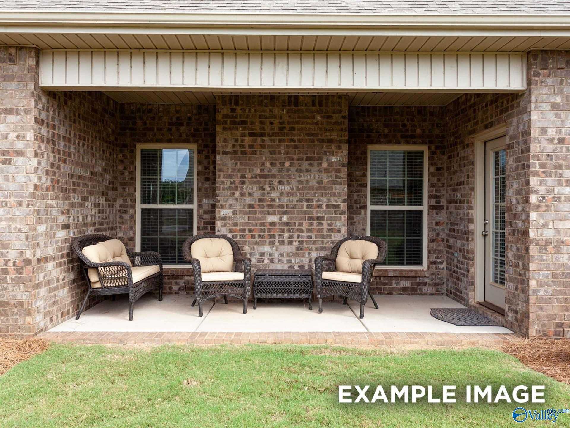 Covered back patio with wicker chairs and coffee table in brick Davidson Homes The Finleigh, Briercreek, Meridianville, Alabama