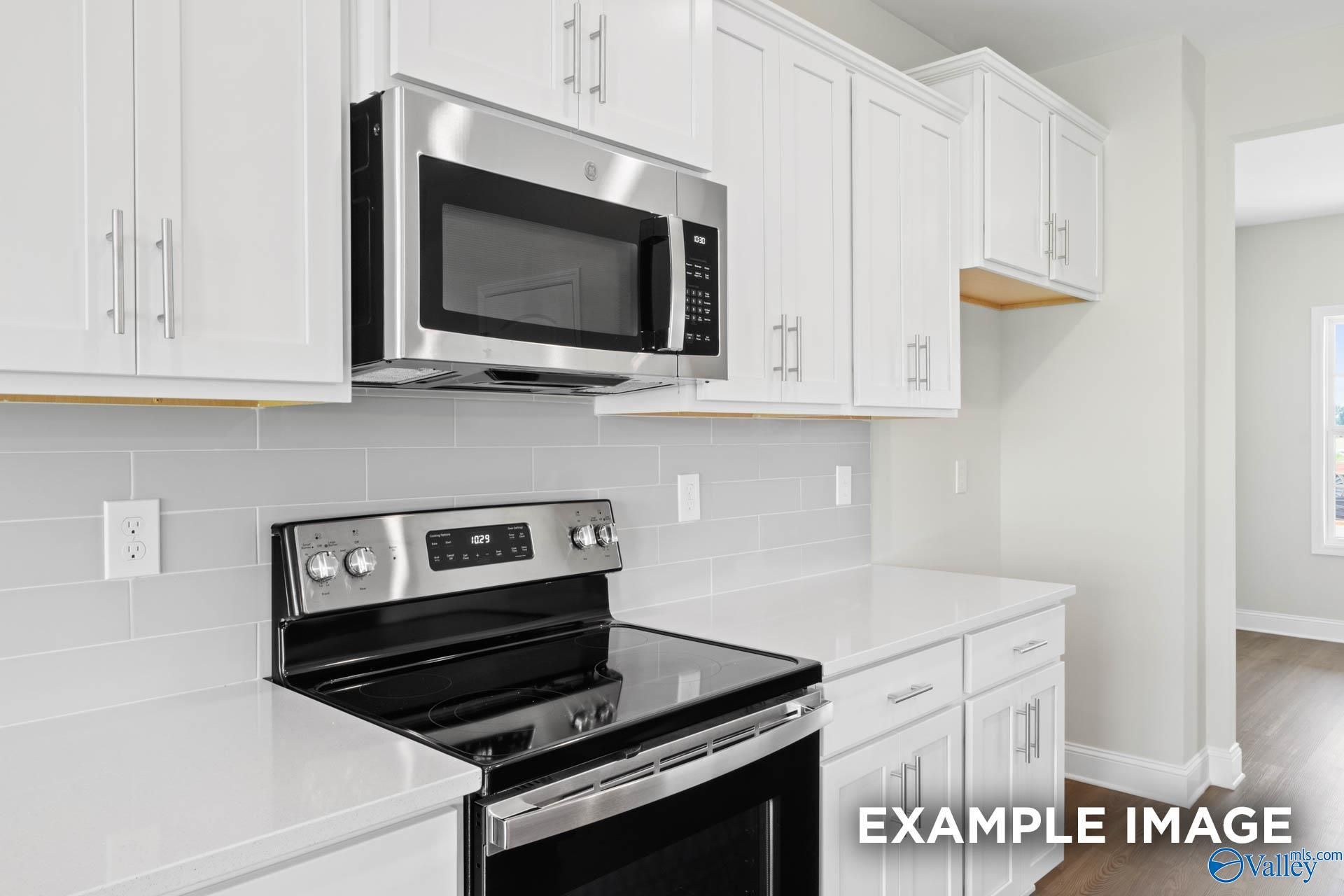 Modern kitchen with white cabinets, quartz countertops, and stainless steel appliances in The Shelby B floor plan home.