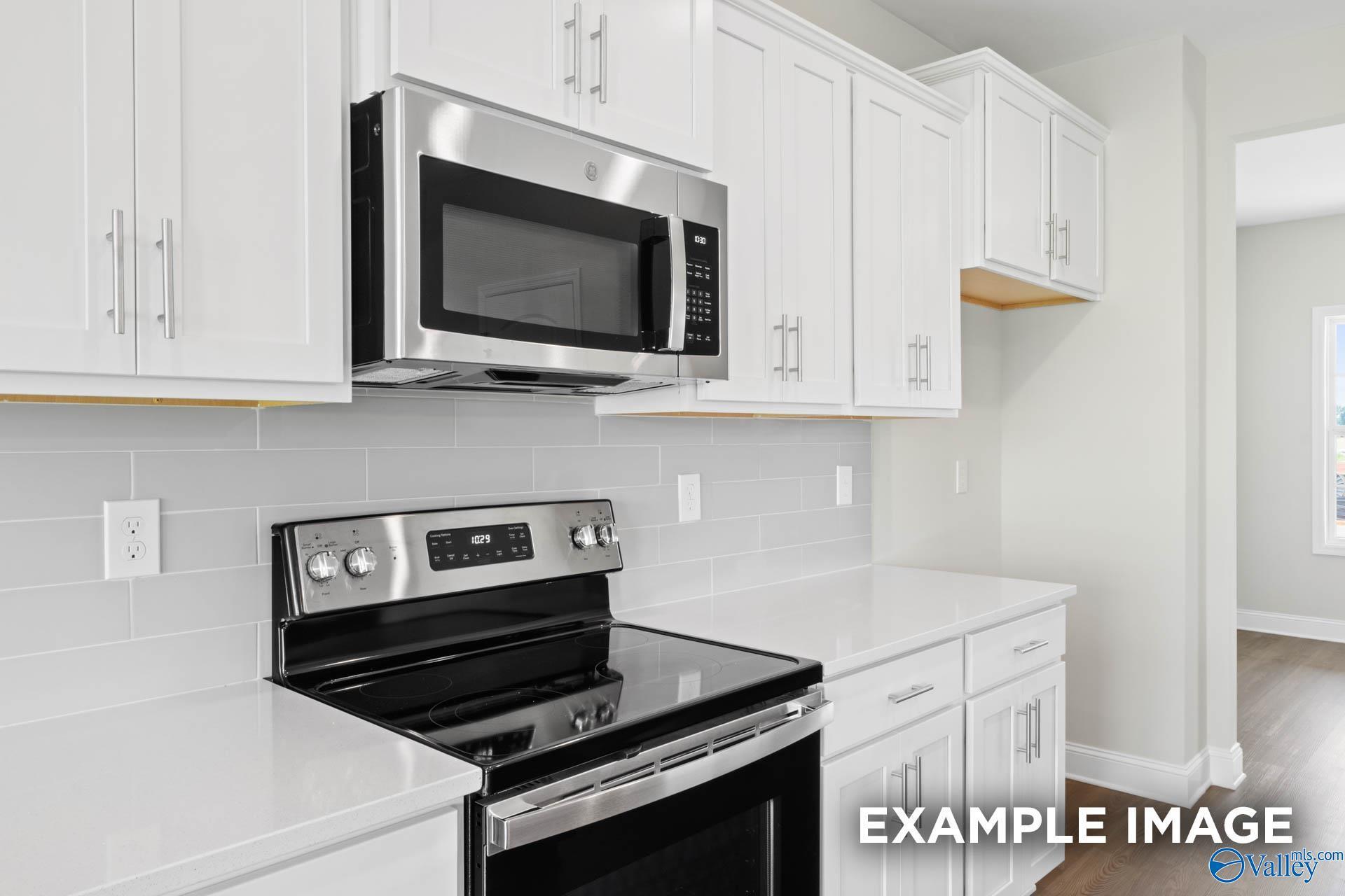 Modern kitchen with white cabinets, quartz countertops, and stainless steel appliances in The Shelby B floor plan home.