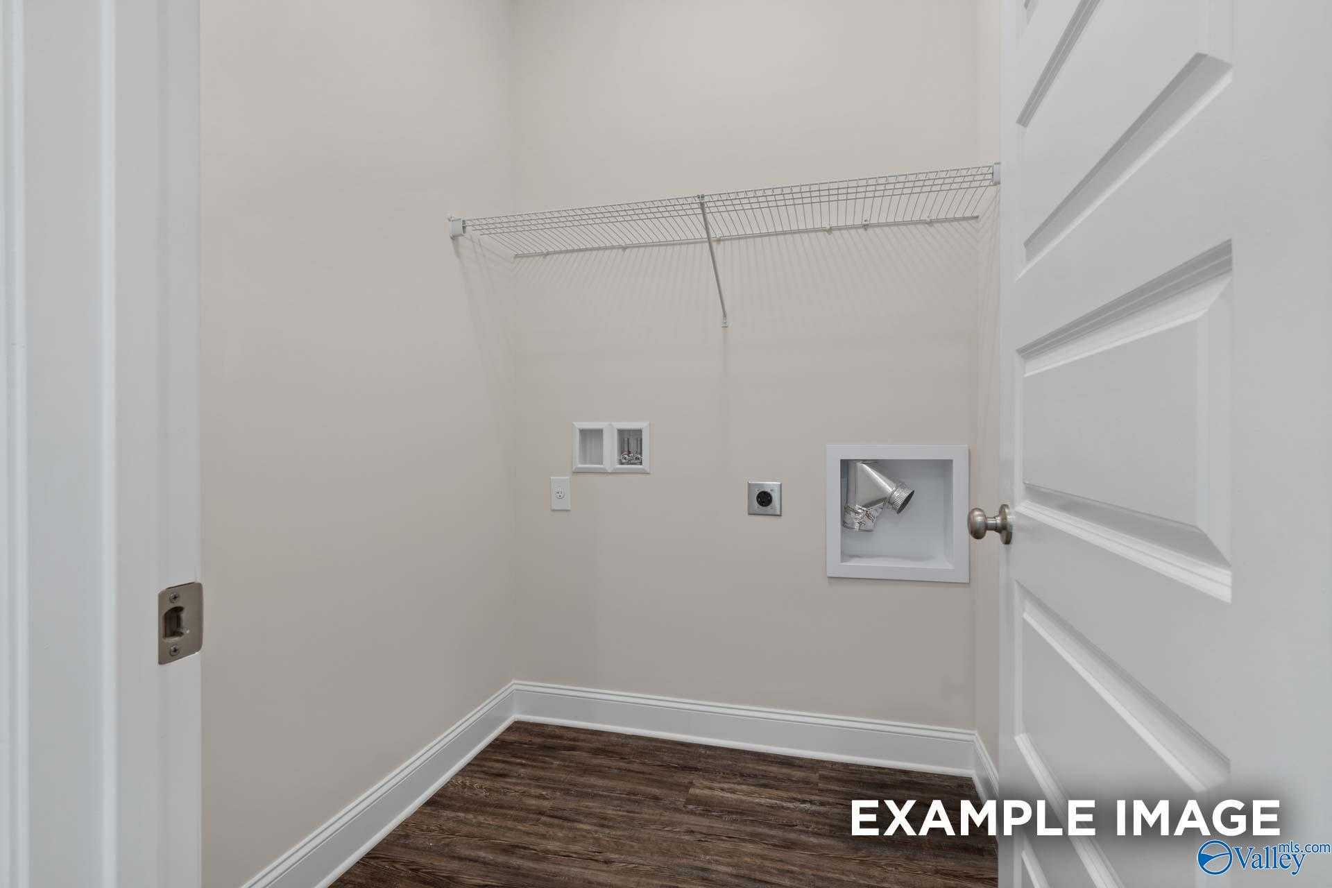 Bright laundry room with washer/dryer hookups, wire shelving, and beige walls in The Asheville floor plan, Arab, Alabama
